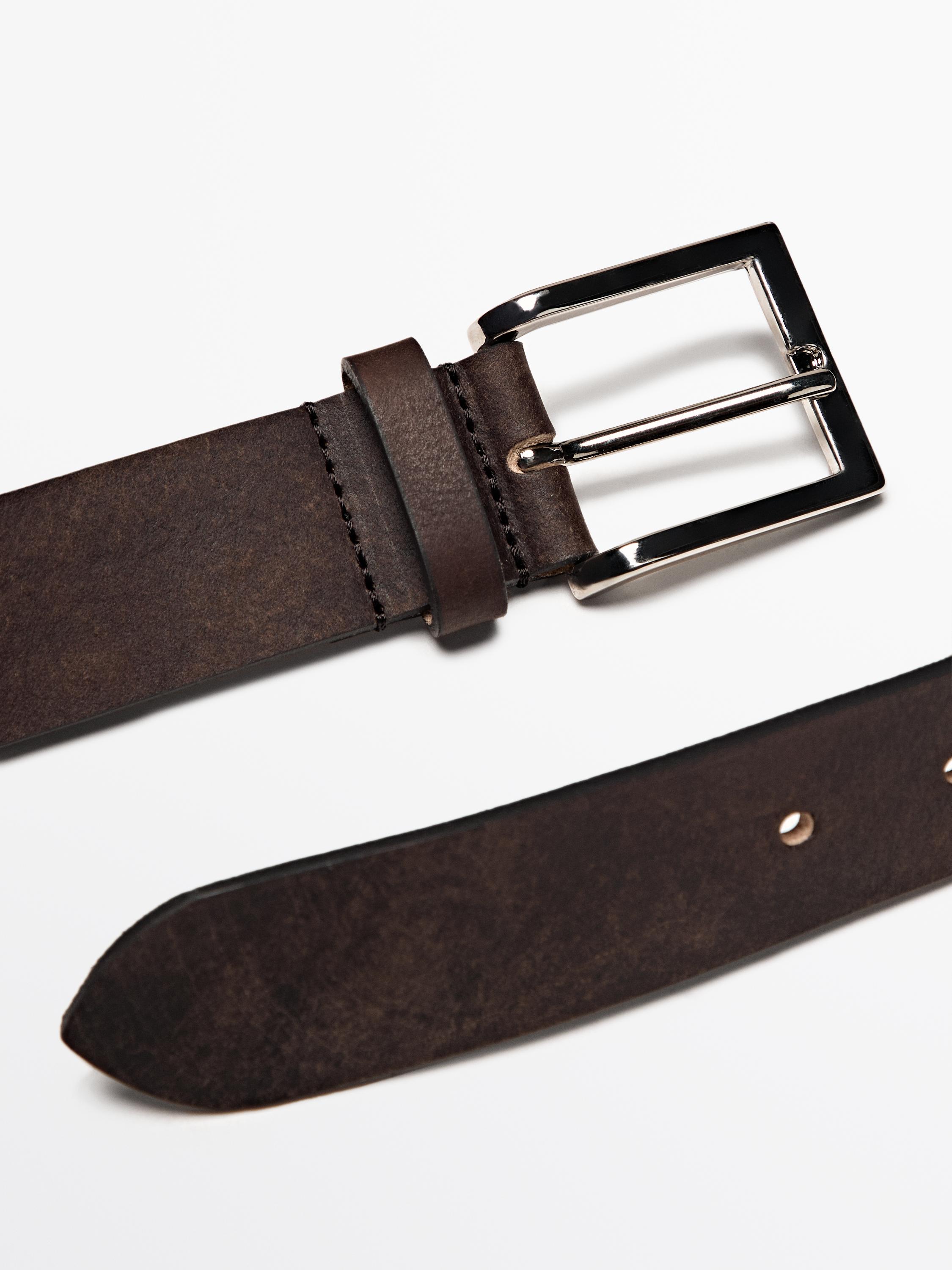 تفاصيل حزام بني داكن مع إبزيم معدني مربع ولمسة نهائية بالية.