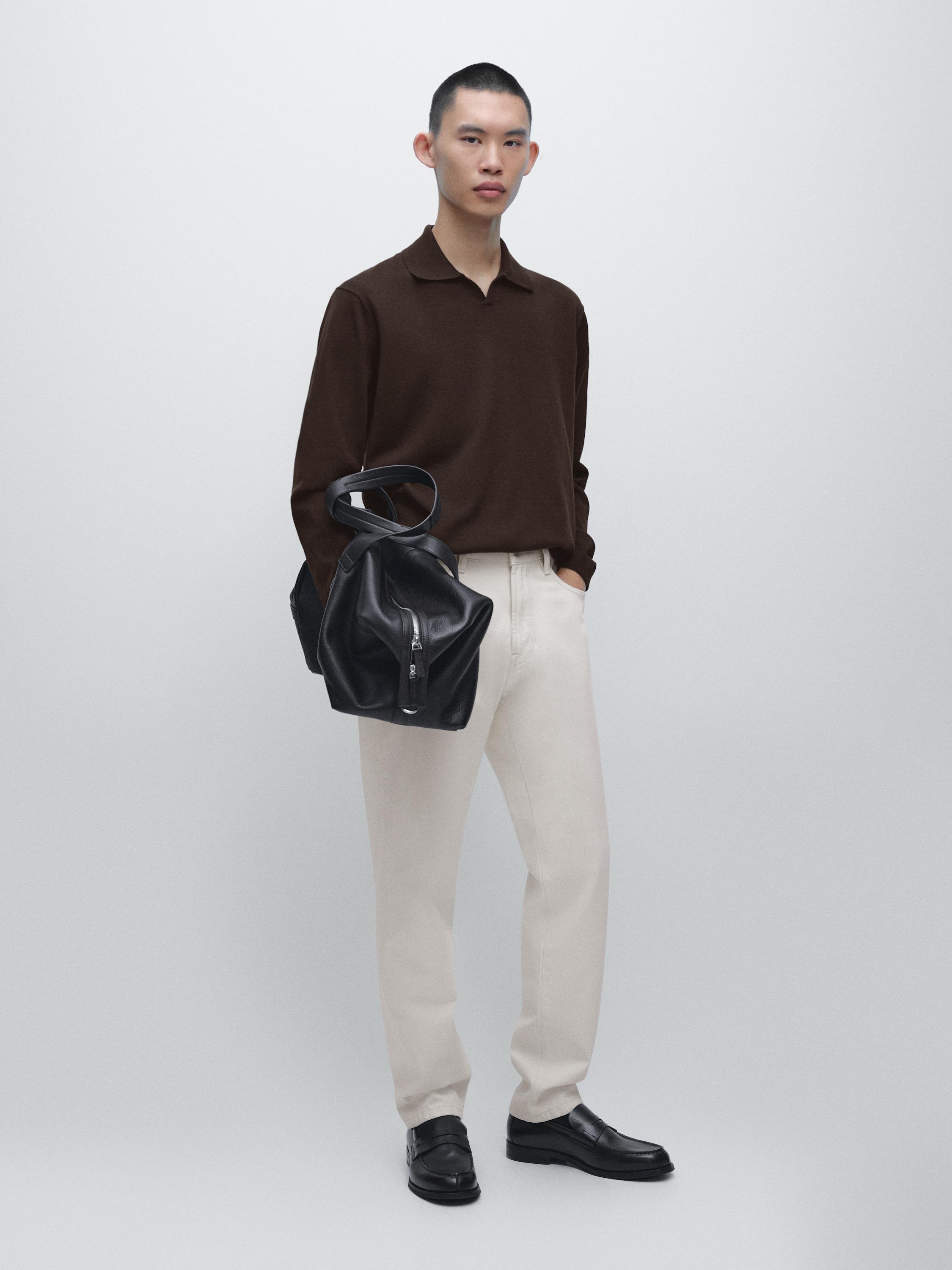 Conjunto de jersey café jaspeado con cuello polo y pantalones beige. Zapatos negros visibles.