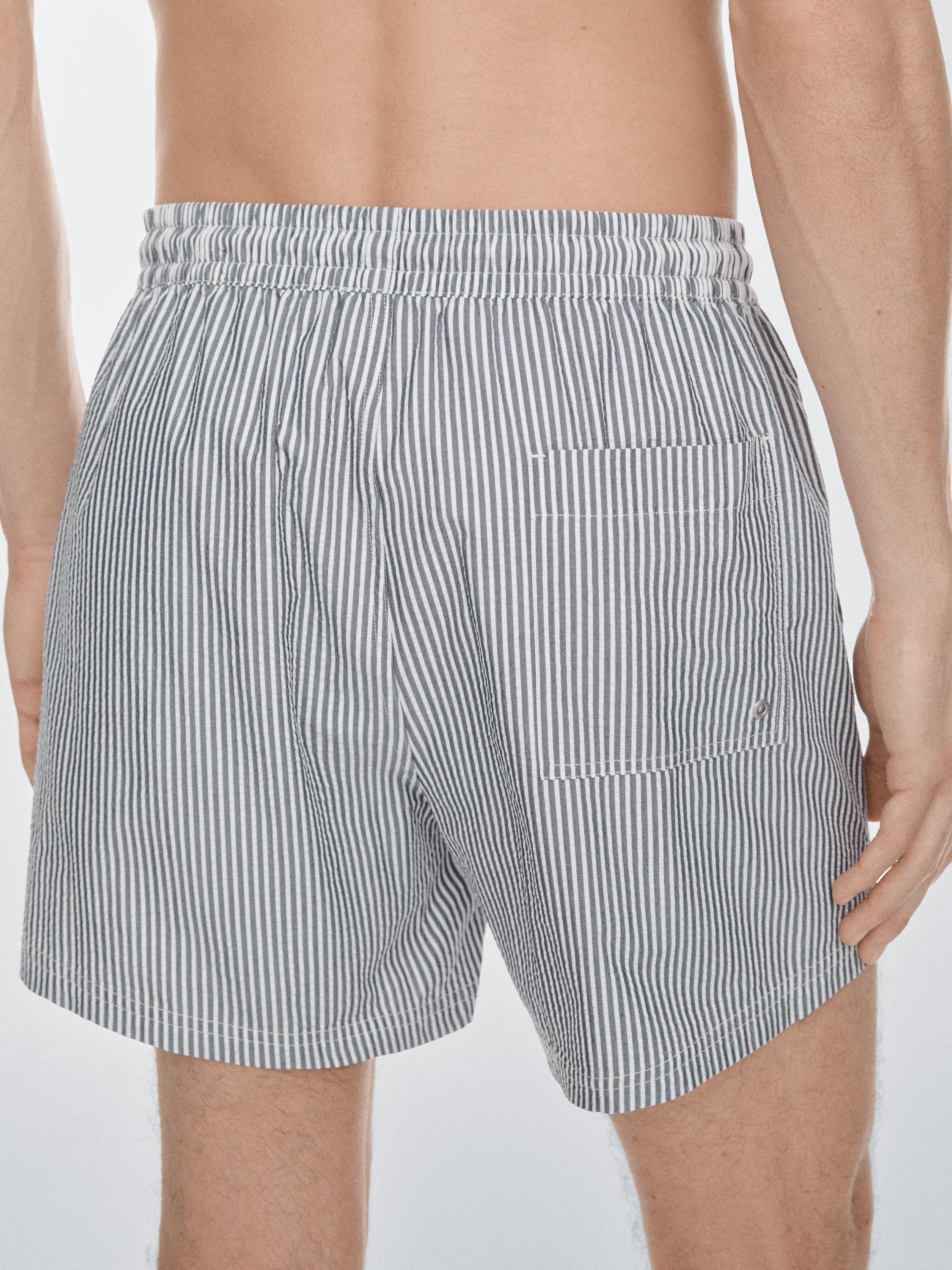 Halbnahe Aufnahme eines marineblauen Badeanzugs mit weißen vertikalen Streifen und einer Gesäßtasche.