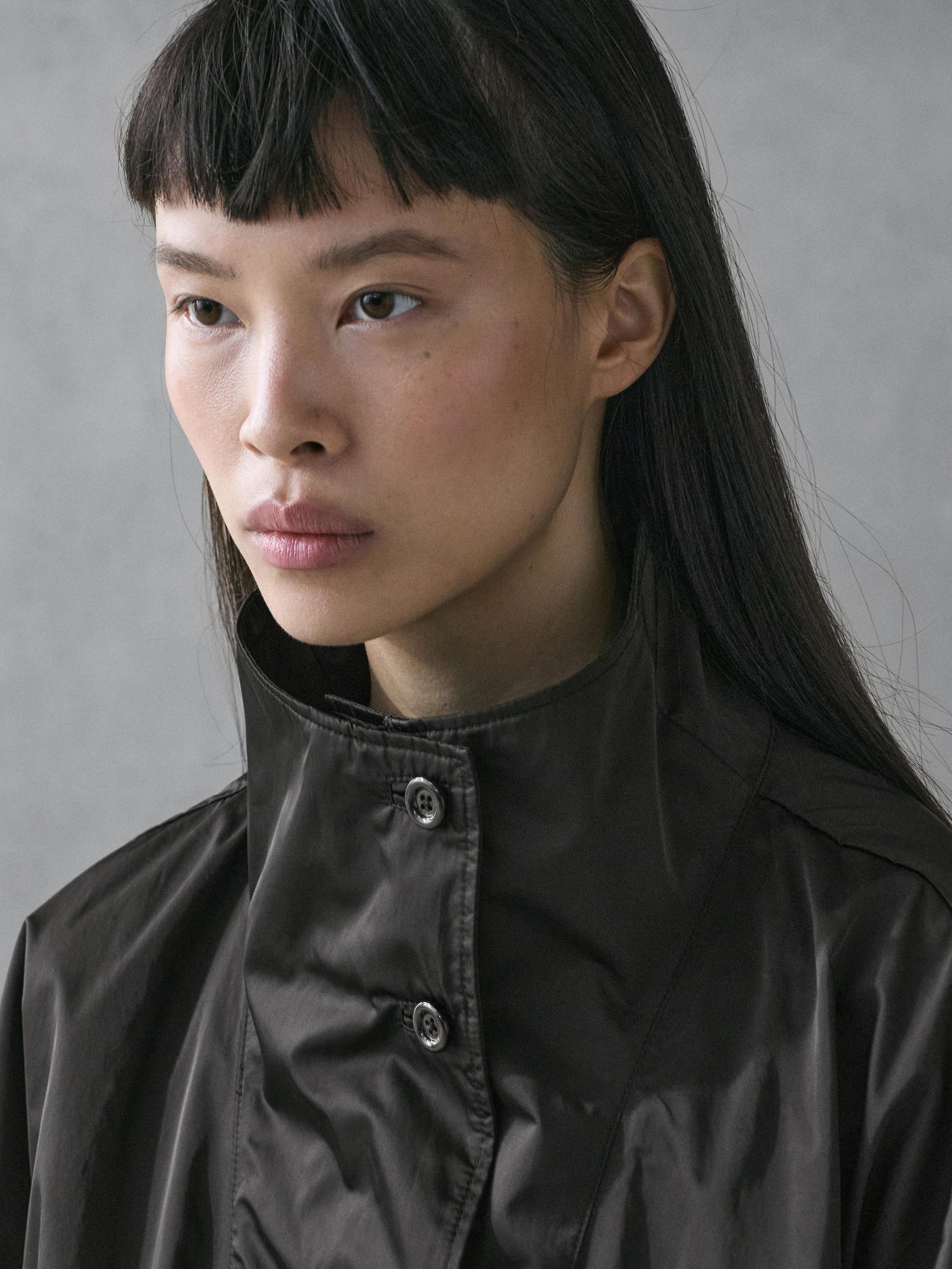 Деталь воротника-стойки с пуговицами синего пальто.