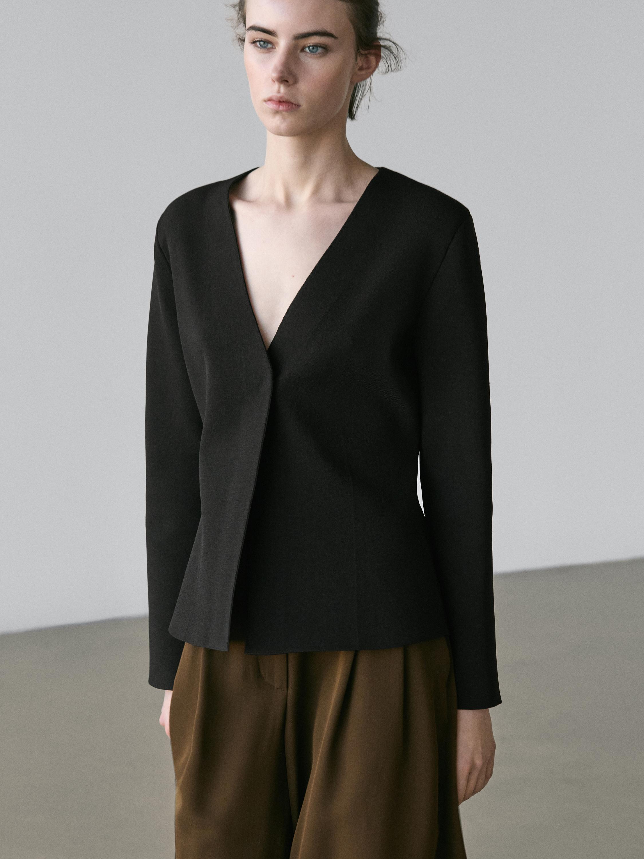Mid-shot of a black cardigan with a V-neck and an asymmetrical front closure.