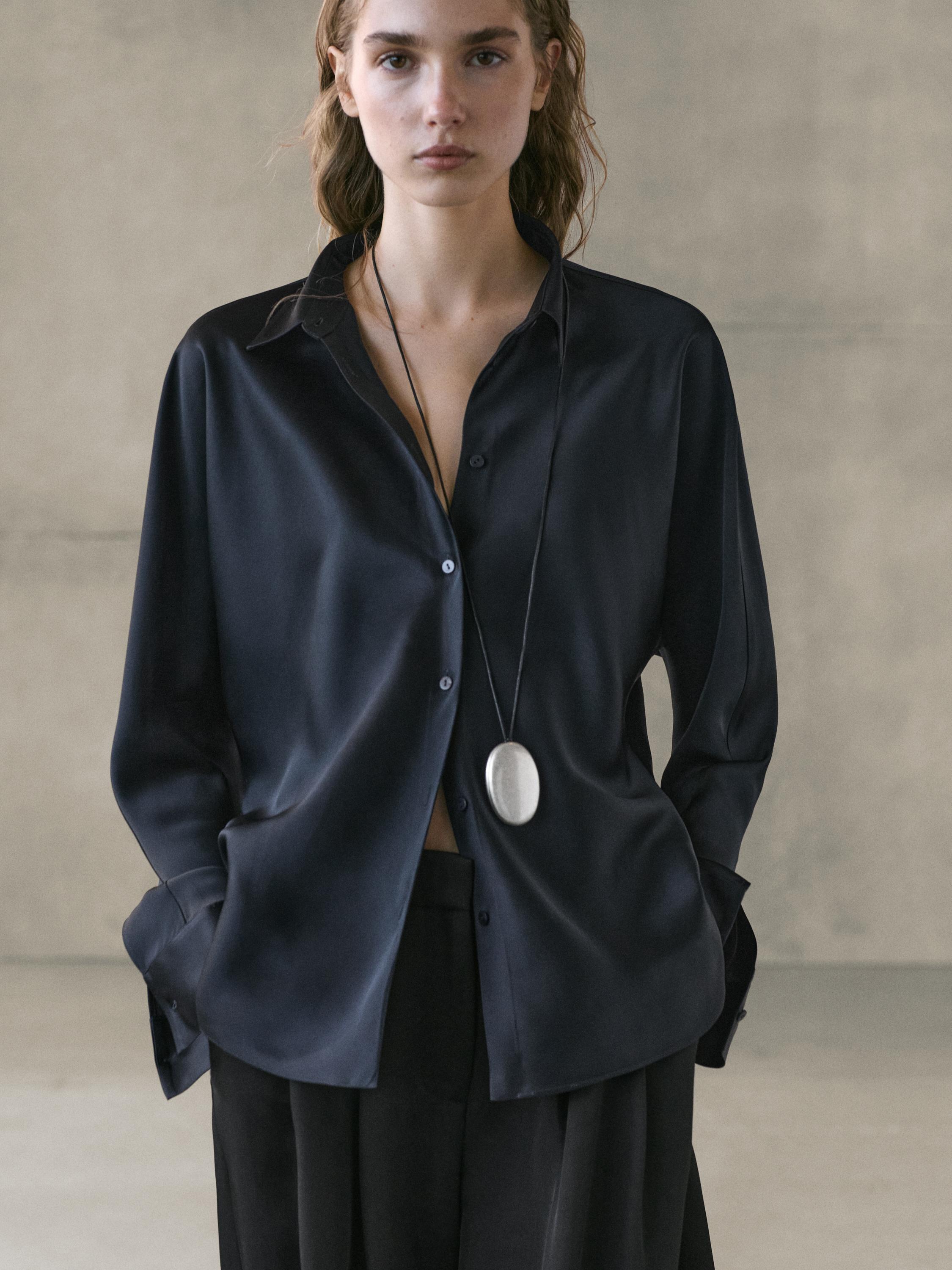 Medium shot of a dark blue satin shirt with buttons and side pockets.