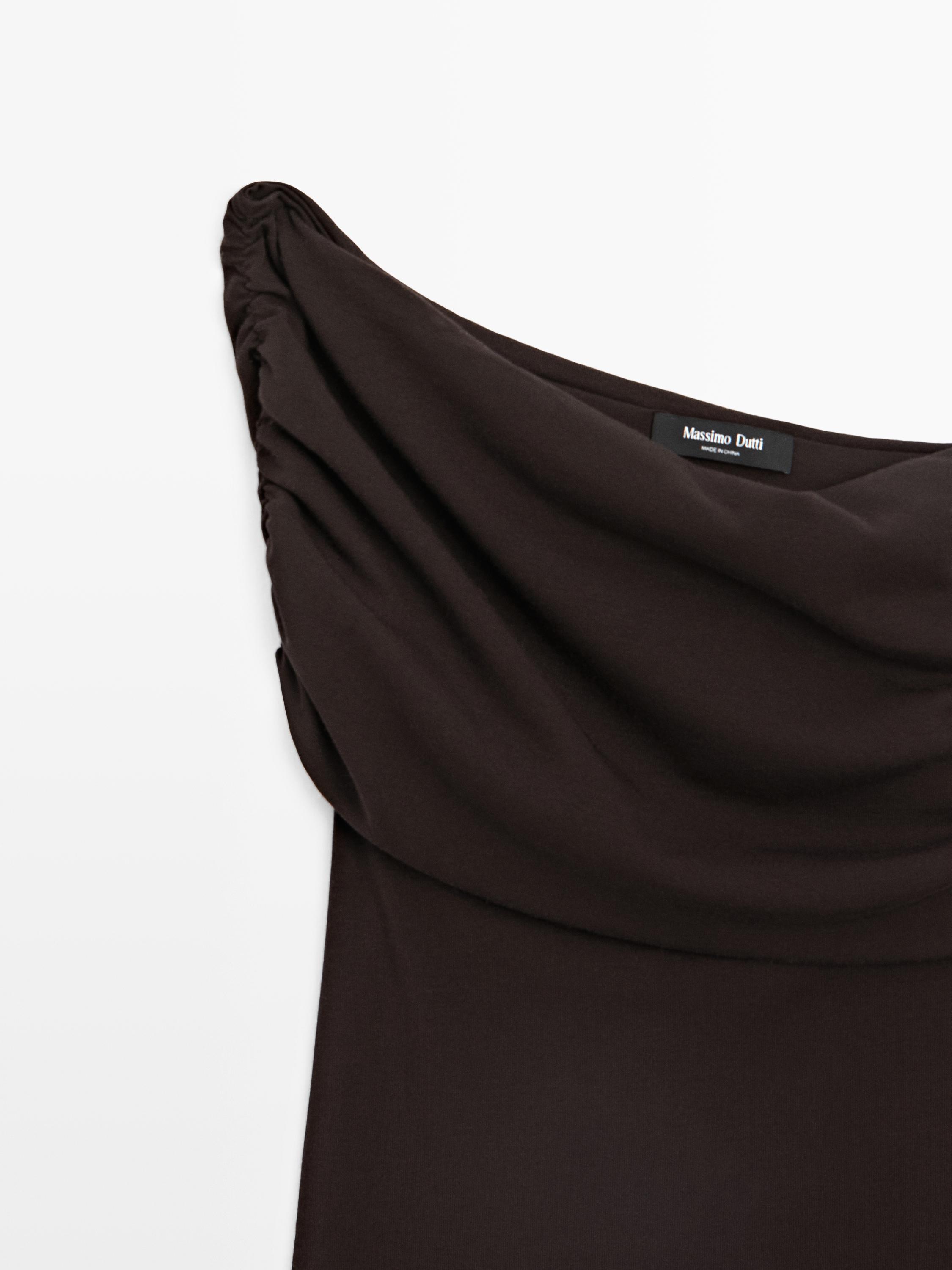 "Detalle de la parte superior de camiseta sin mangas café con fruncido en el hombro."