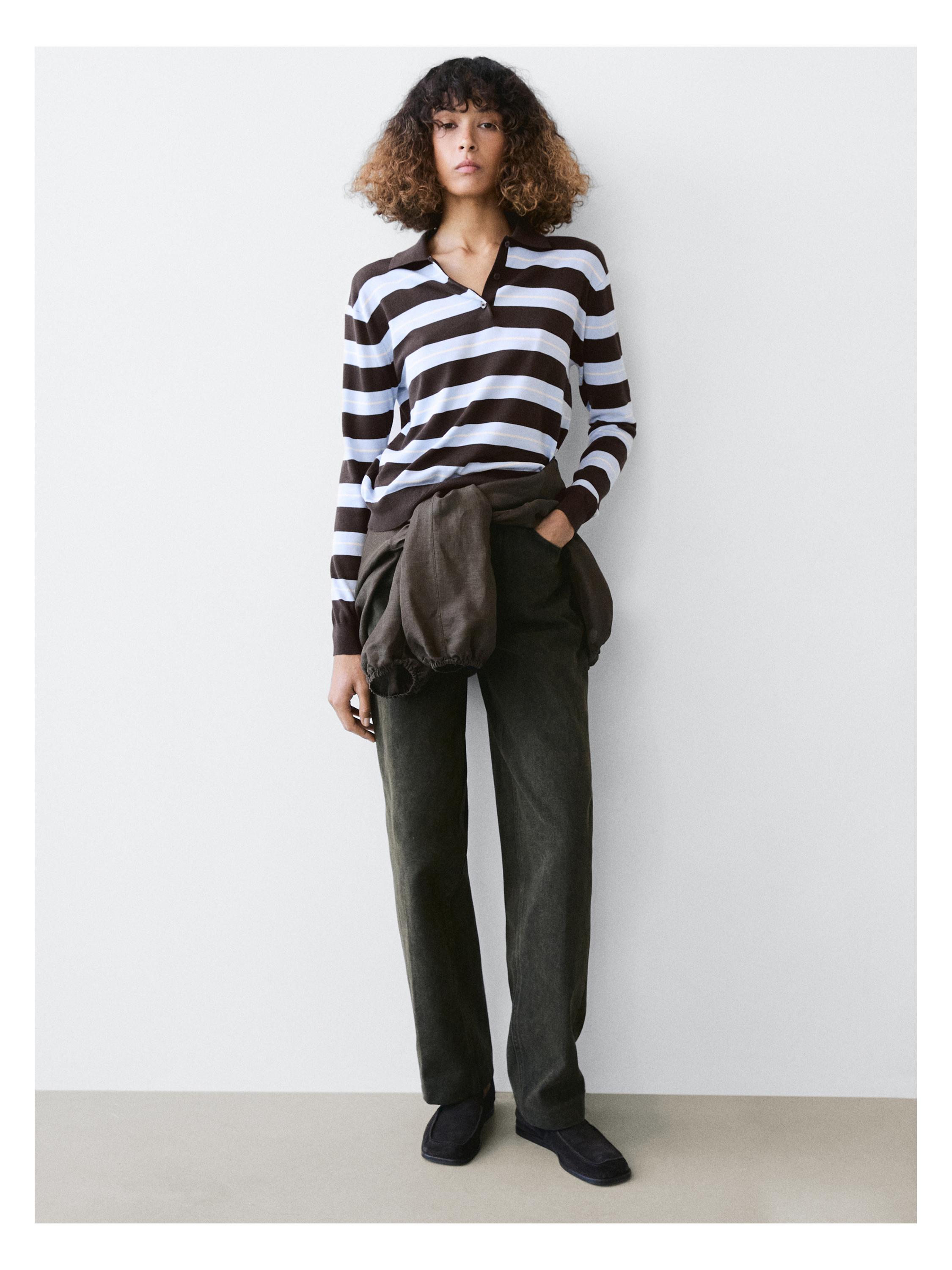 Kompleti xhupi polo me vija kafe dhe të bardha, pantallona të errëta dhe xhaketë kafe e lidhur në bel.