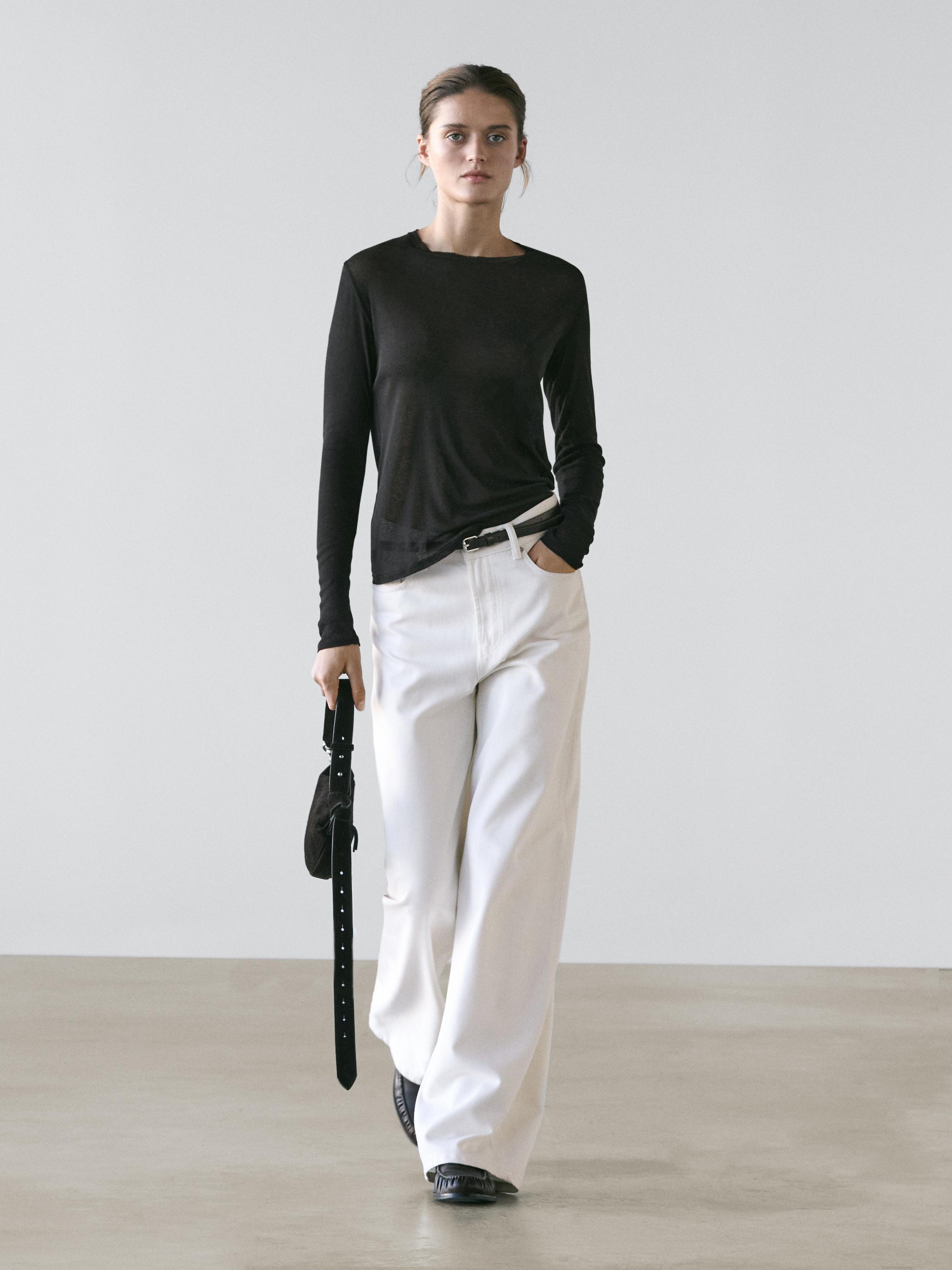 Set aus schwarzem, halbtransparentem Langarmshirt und weißer weiter Hose mit Seitentaschen.