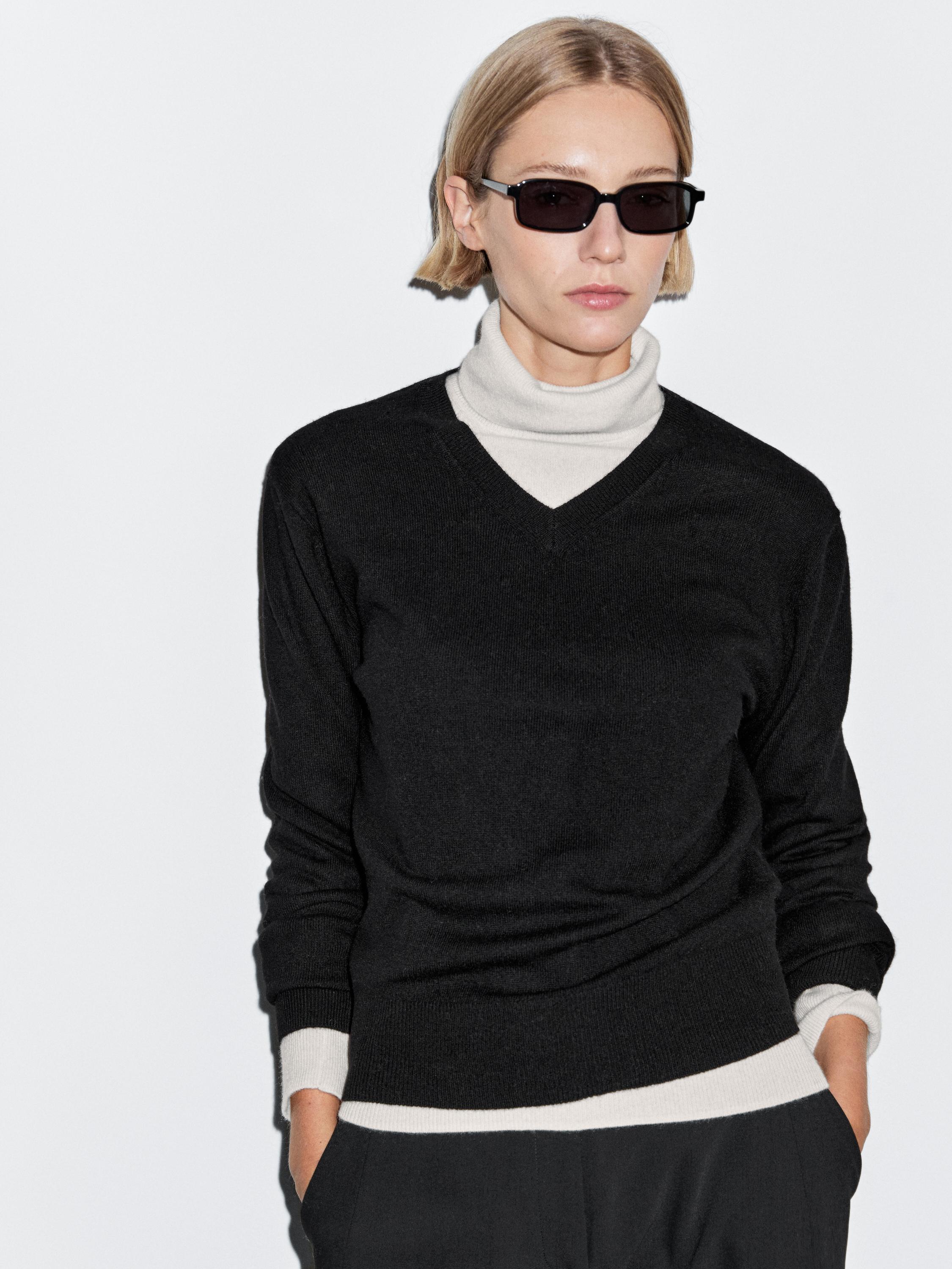 Medium shot of a heather gray jersey with a V-neck, contrasting white cuffs and hem, over a white turtleneck.