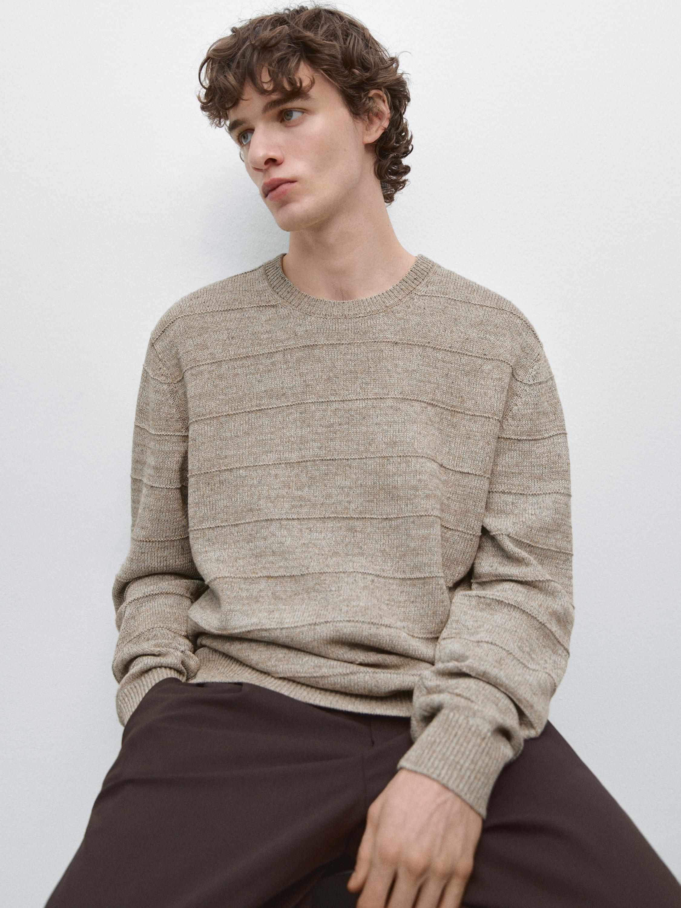 Conjunto de jersey color visón de rayas con cuello redondo y pantalones oscuros.