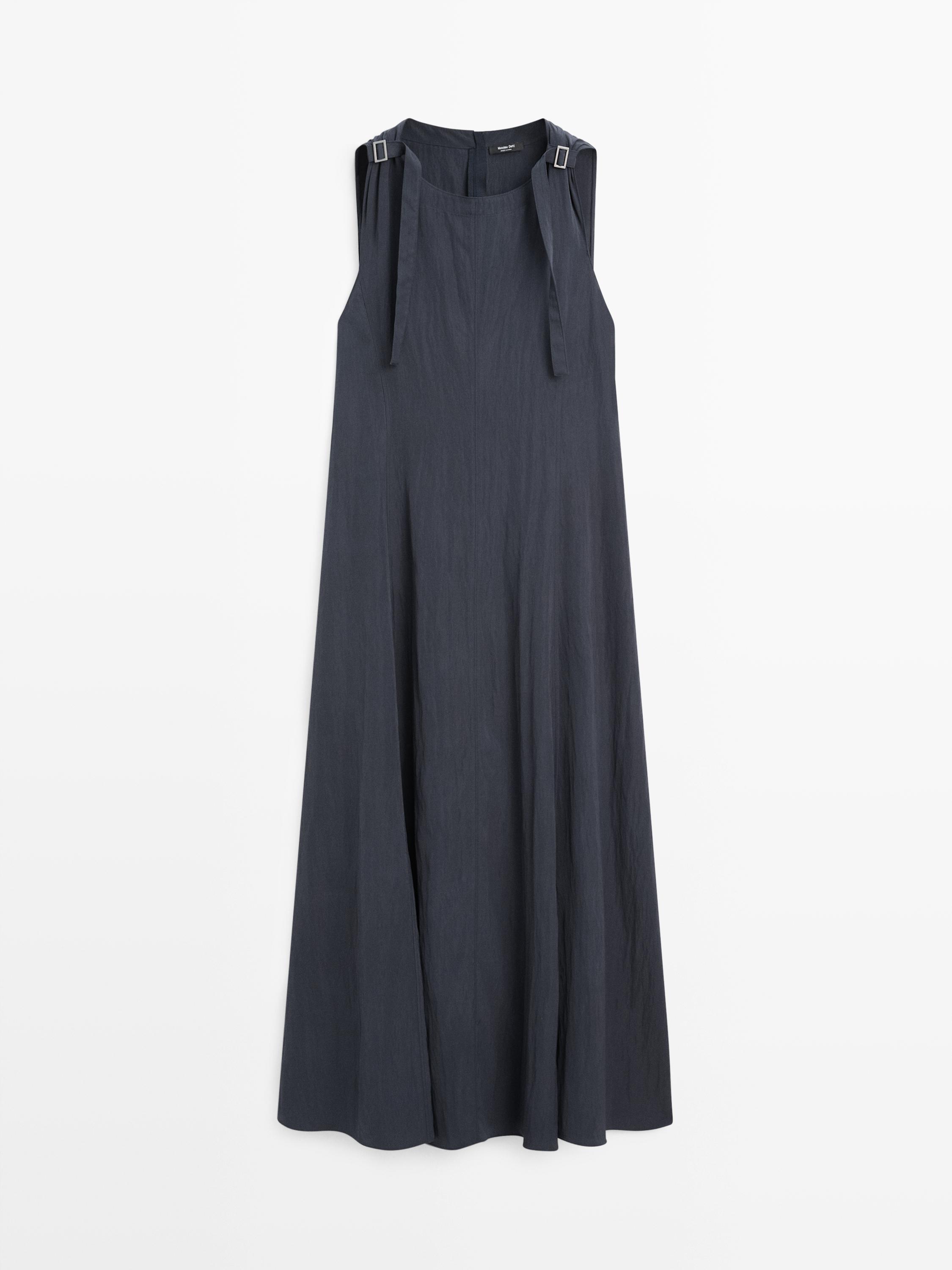 Vista frontal de vestido midi azul gris sin mangas, con detalle de hebillas en los tirantes y corte fluido.
