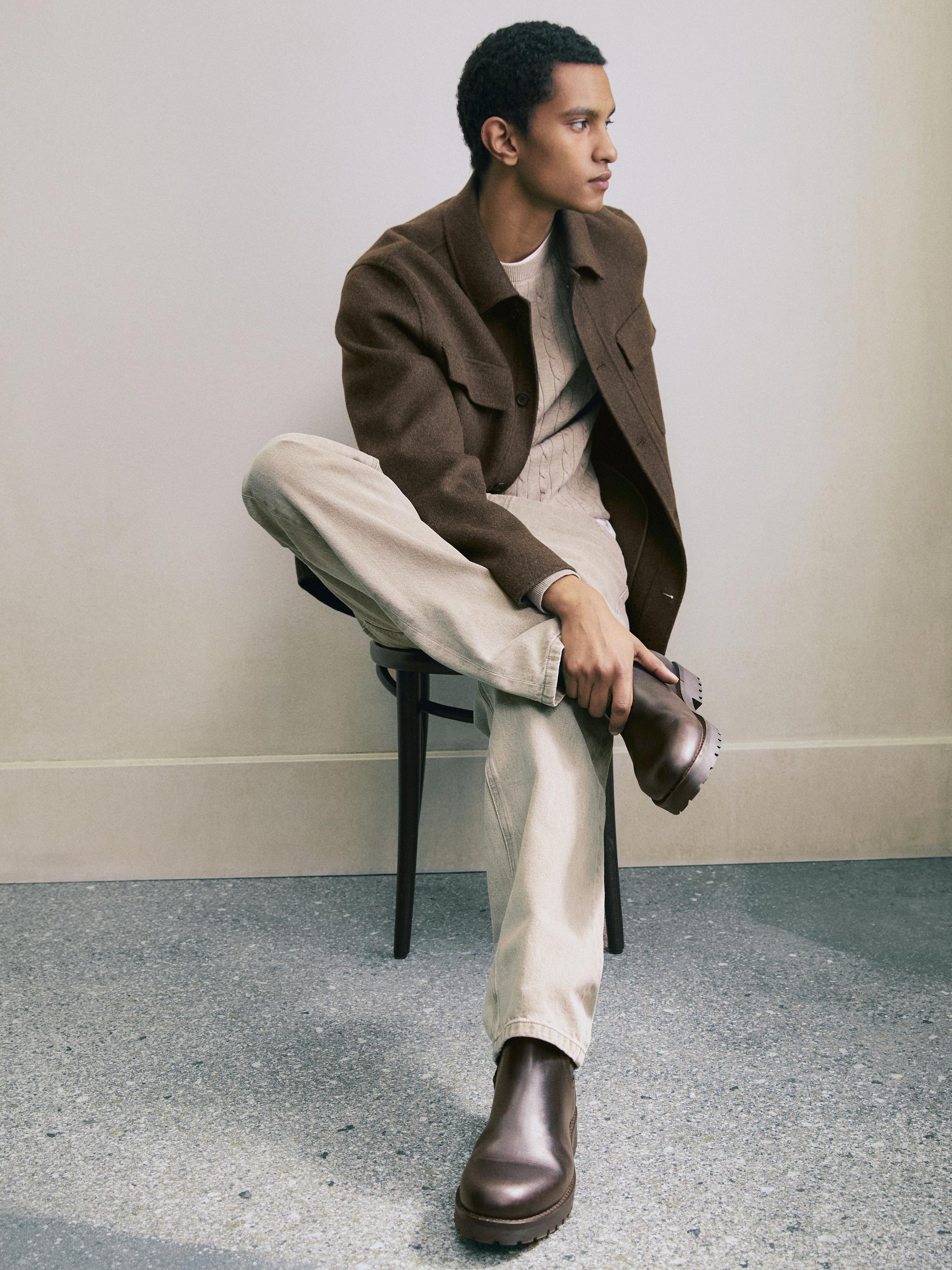 Braunes Overshirt-Set mit Taschen, beigem Pullover, heller Hose und braunen Stiefeln.