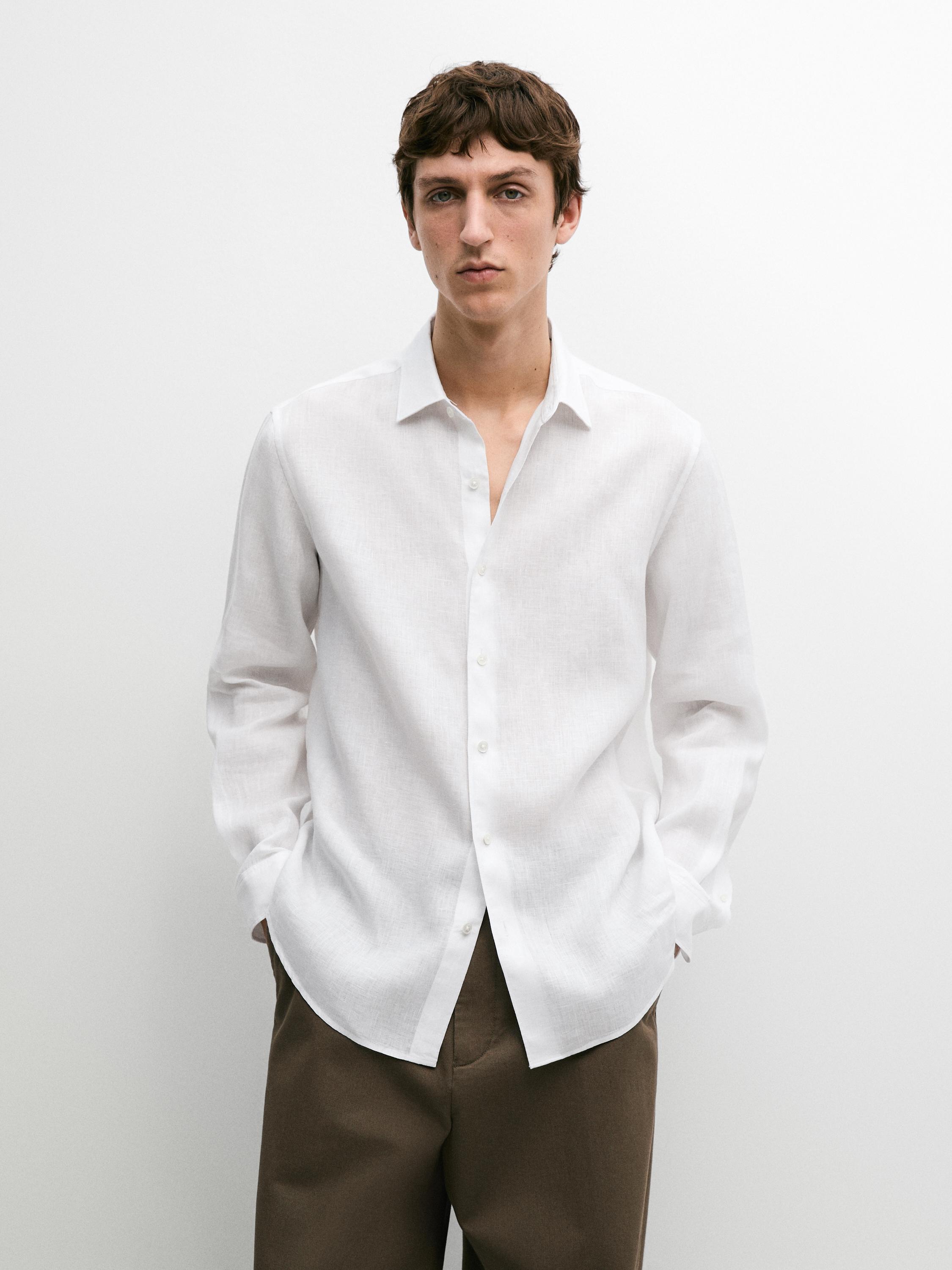 Witte blouse met lange mouwen en knopen en een bruine broek.