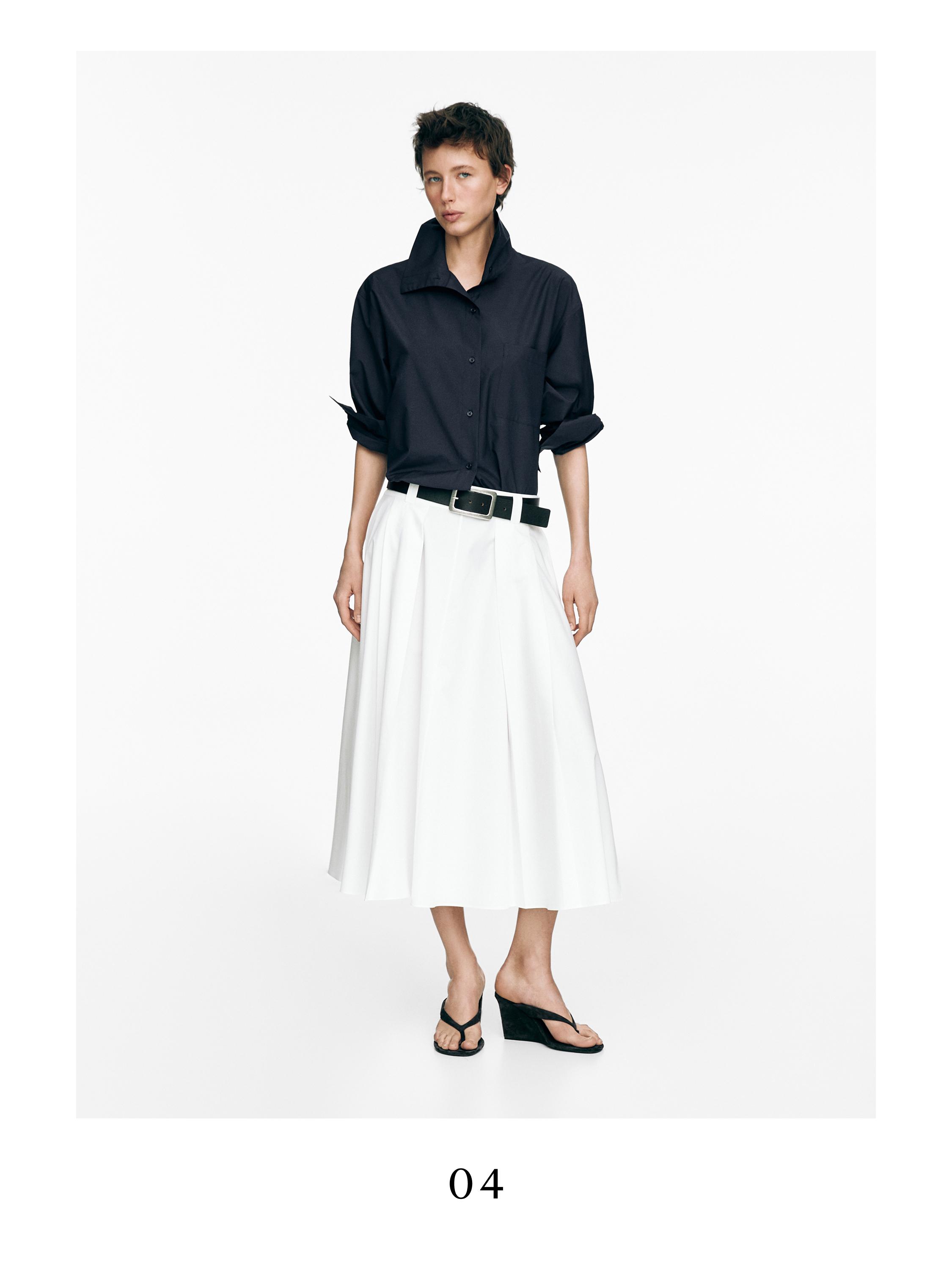 Σύνολο μαύρης μπλούζας με γυριστά μανίκια και λευκή μίντι φούστα με θηλιές και πιέτες.