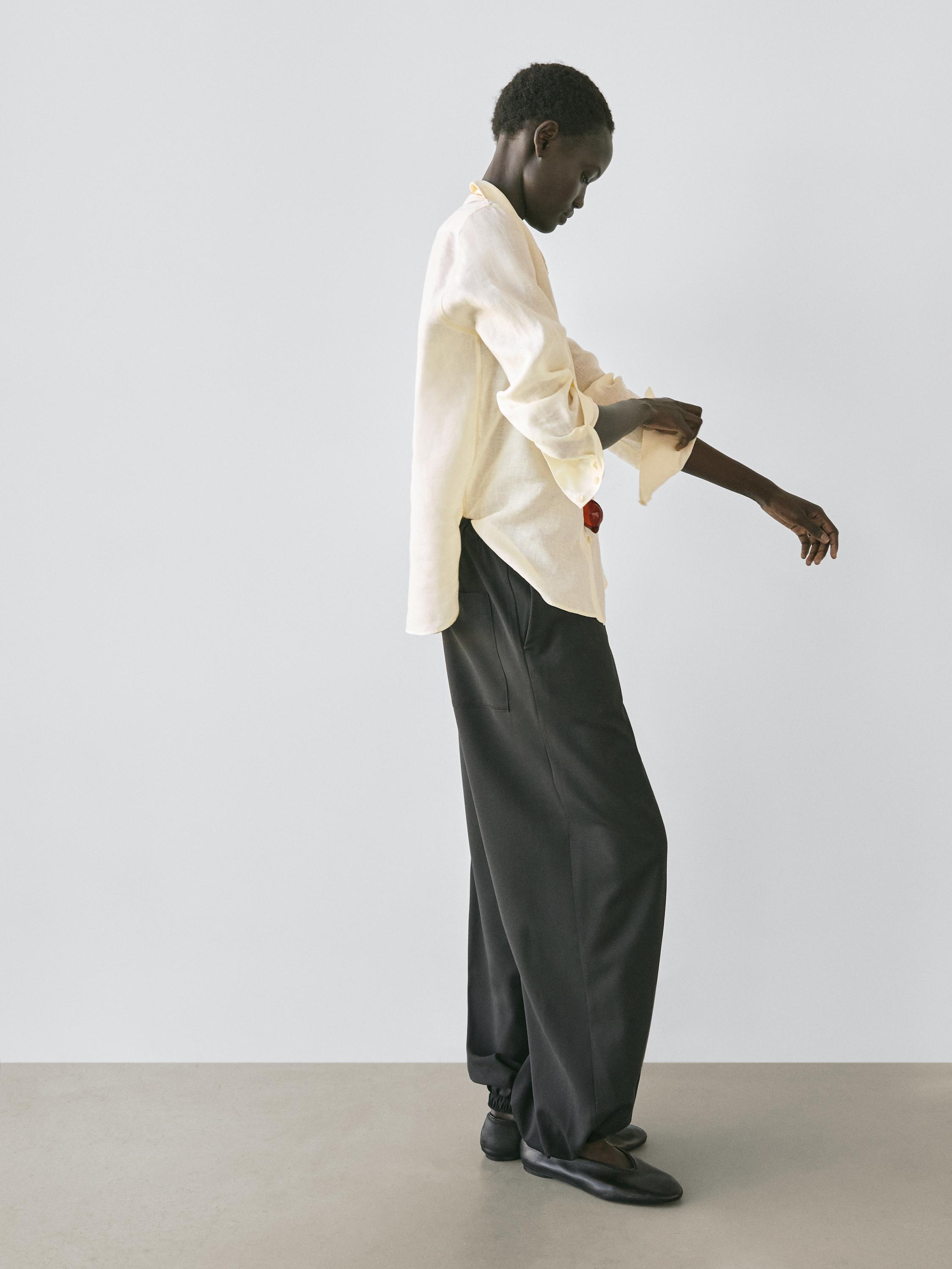 Set kemeja kuning longgar lengan panjang dan celana panjang hitam lebar dengan saku samping.