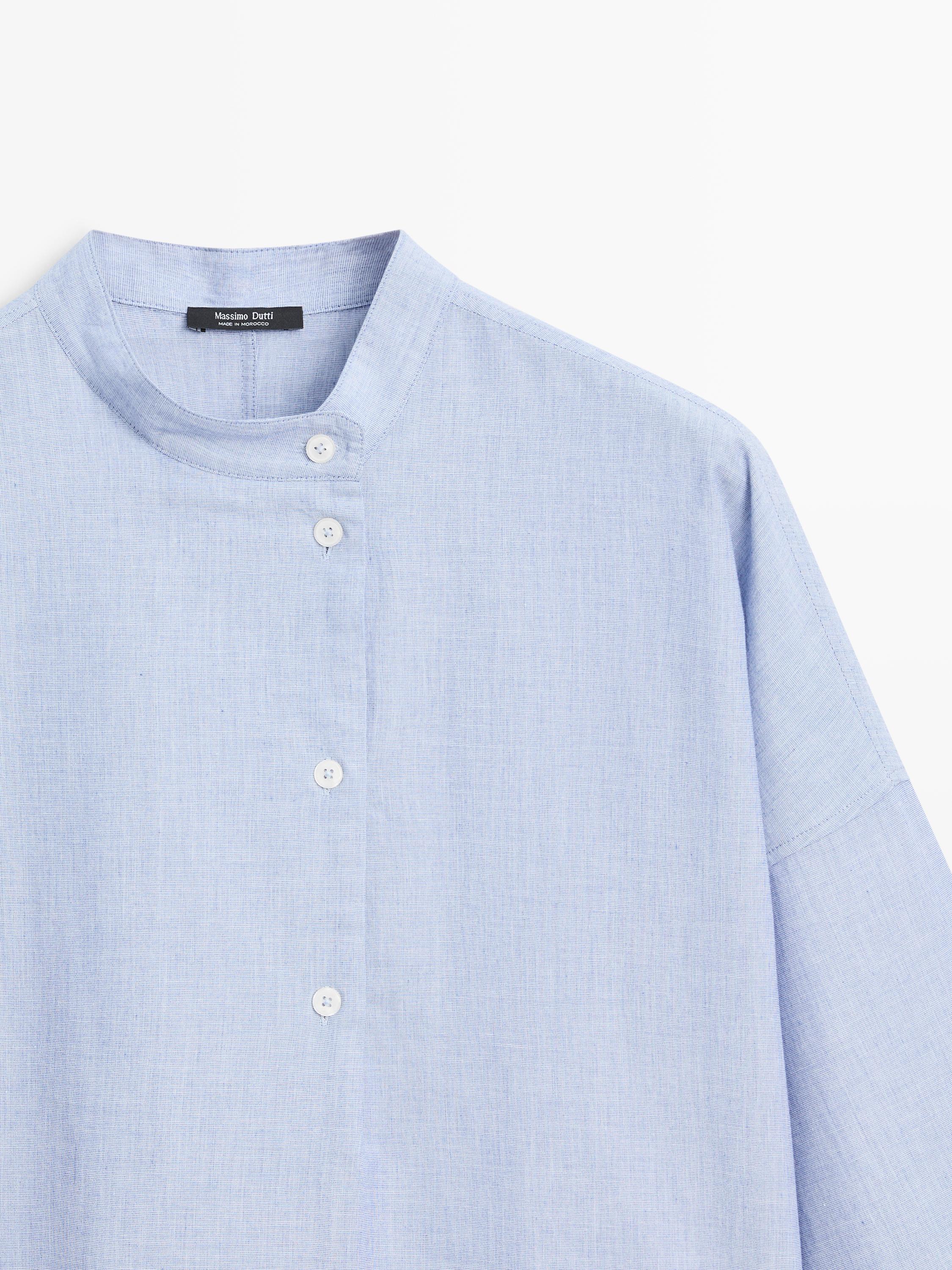 "Detale kołnierza i zapięcia dżinsowej niebieskiej bluzki z białymi guzikami."