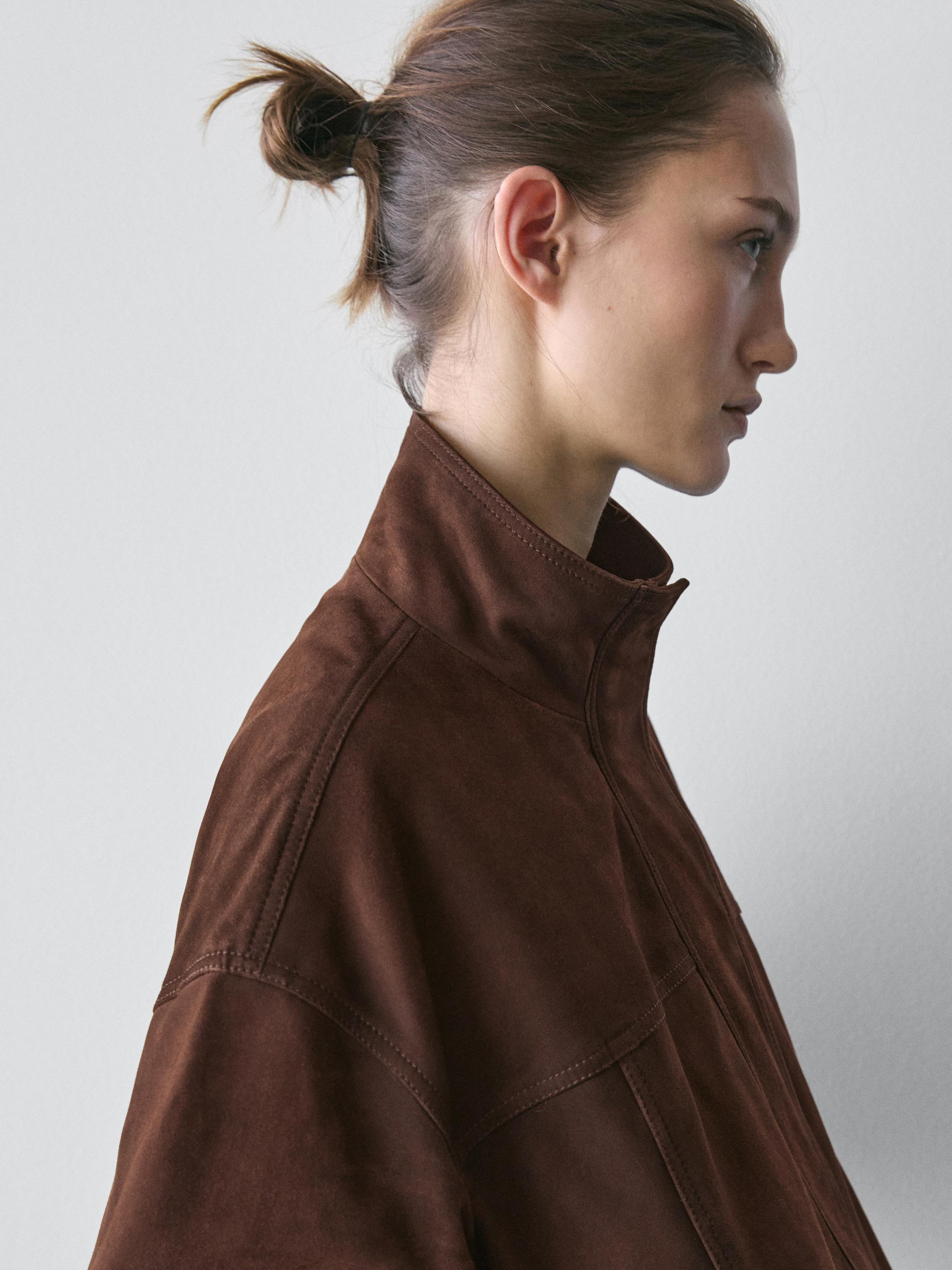 Plano medio de chaqueta bomber marrón con cuello alto y costuras visibles.