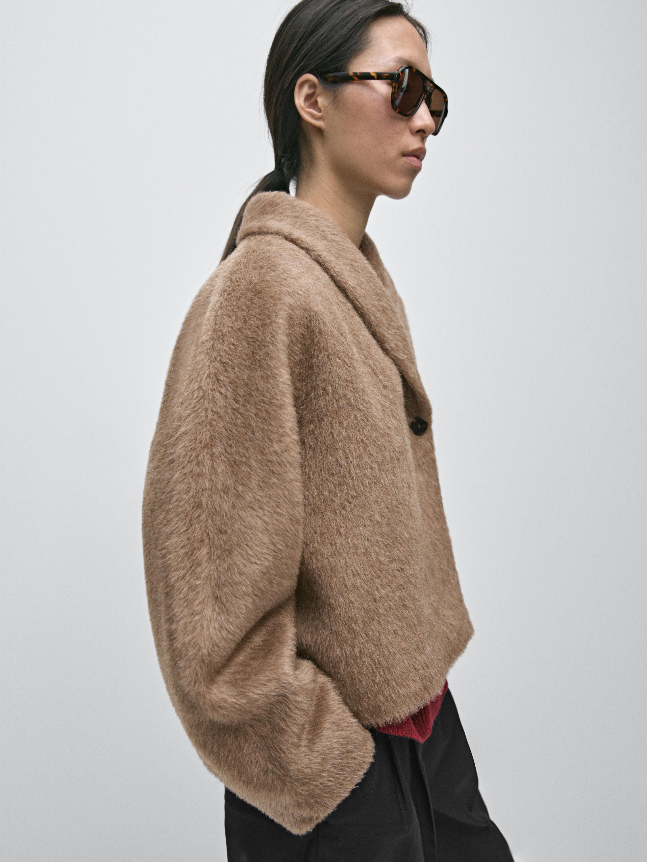 ภาพกลางของเสื้อแจ็คเก็ตครอปสีน้ำตาลเทาแบบกระดุมสองแถว คอปกกว้าง และกระดุมที่มองเห็นได้