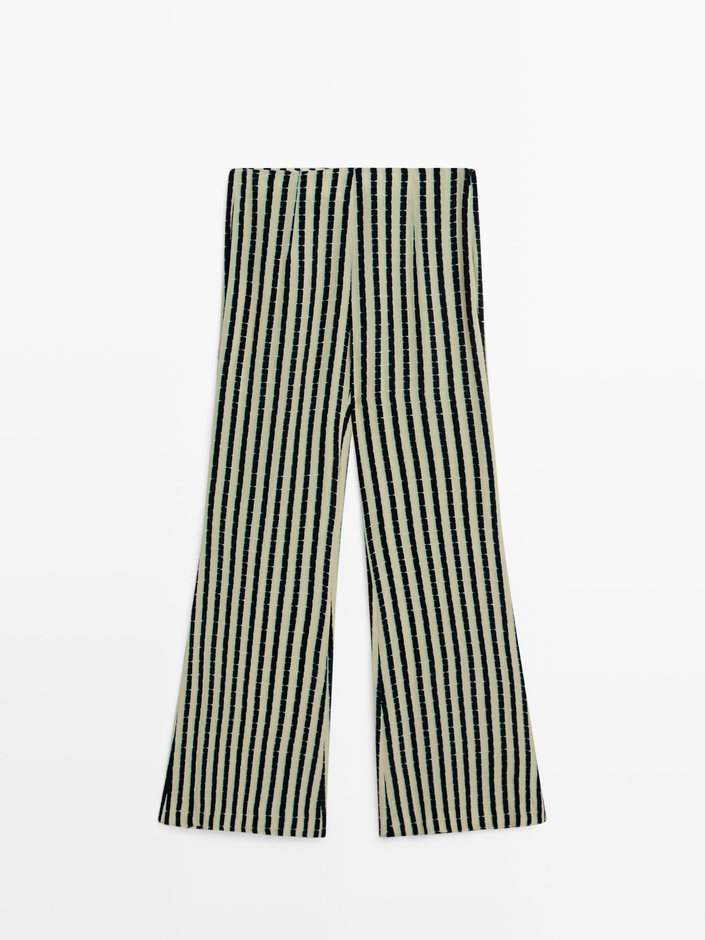 Vista frontal de pantalón de rayas verticales en verde agua y negro, corte recto y pernera ancha.