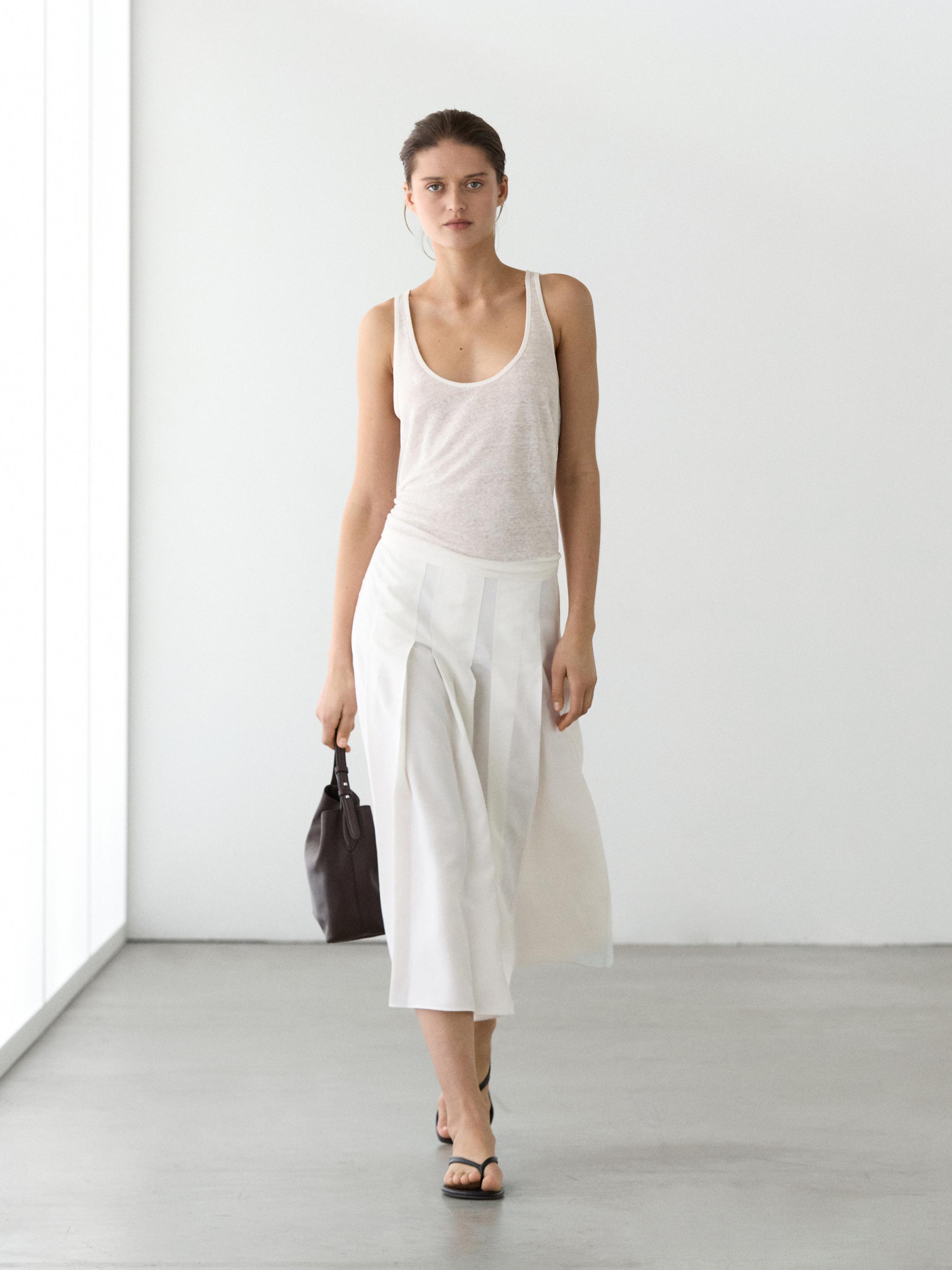 Conjunto de falda midi blanca con tablas y camiseta sin mangas blanca.