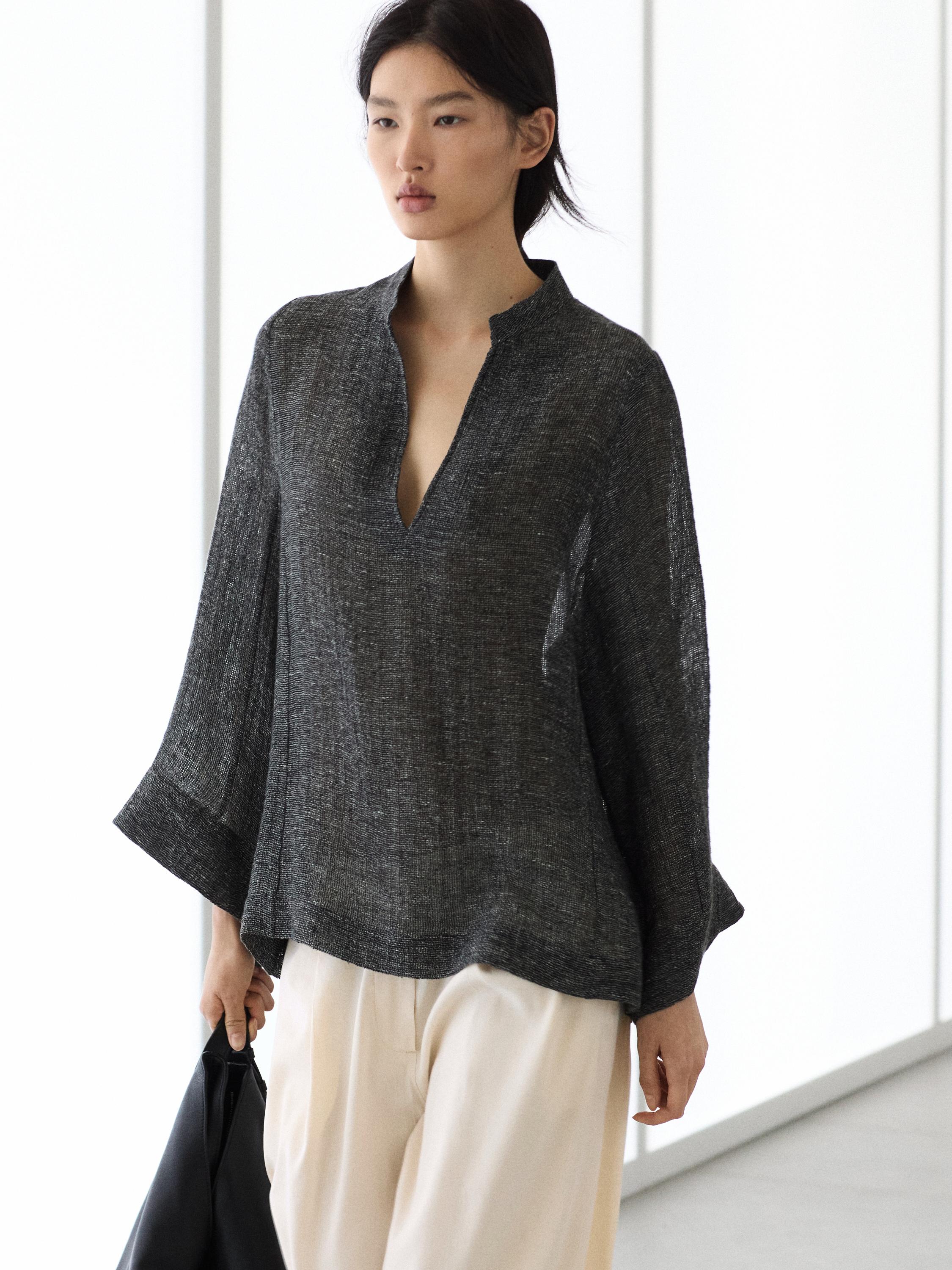 Ensemble blouse grise à manches longues et col en V avec pantalon blanc ample.