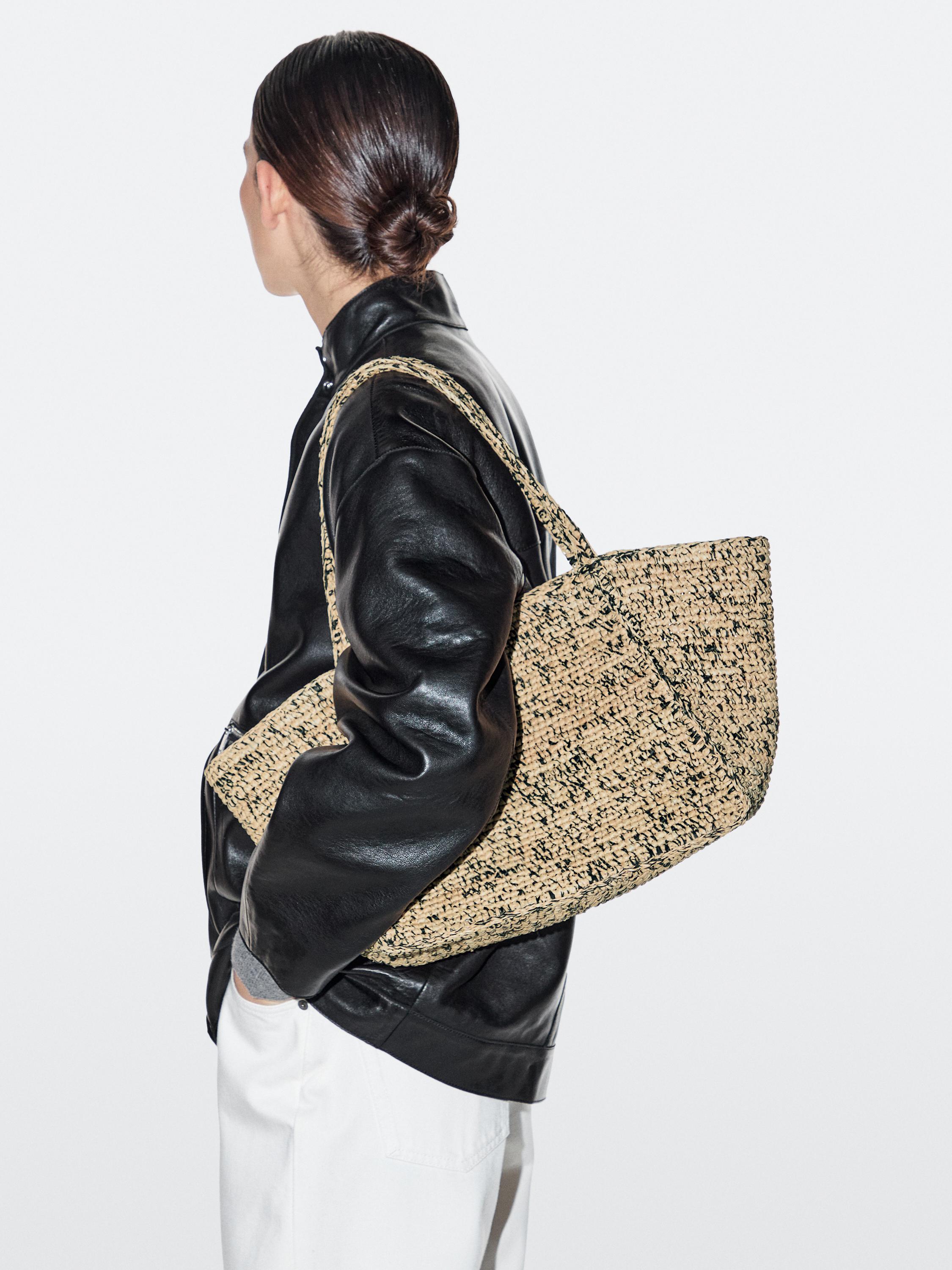 Conxunto de chaqueta negra e bolso tecido beis con asas longas.