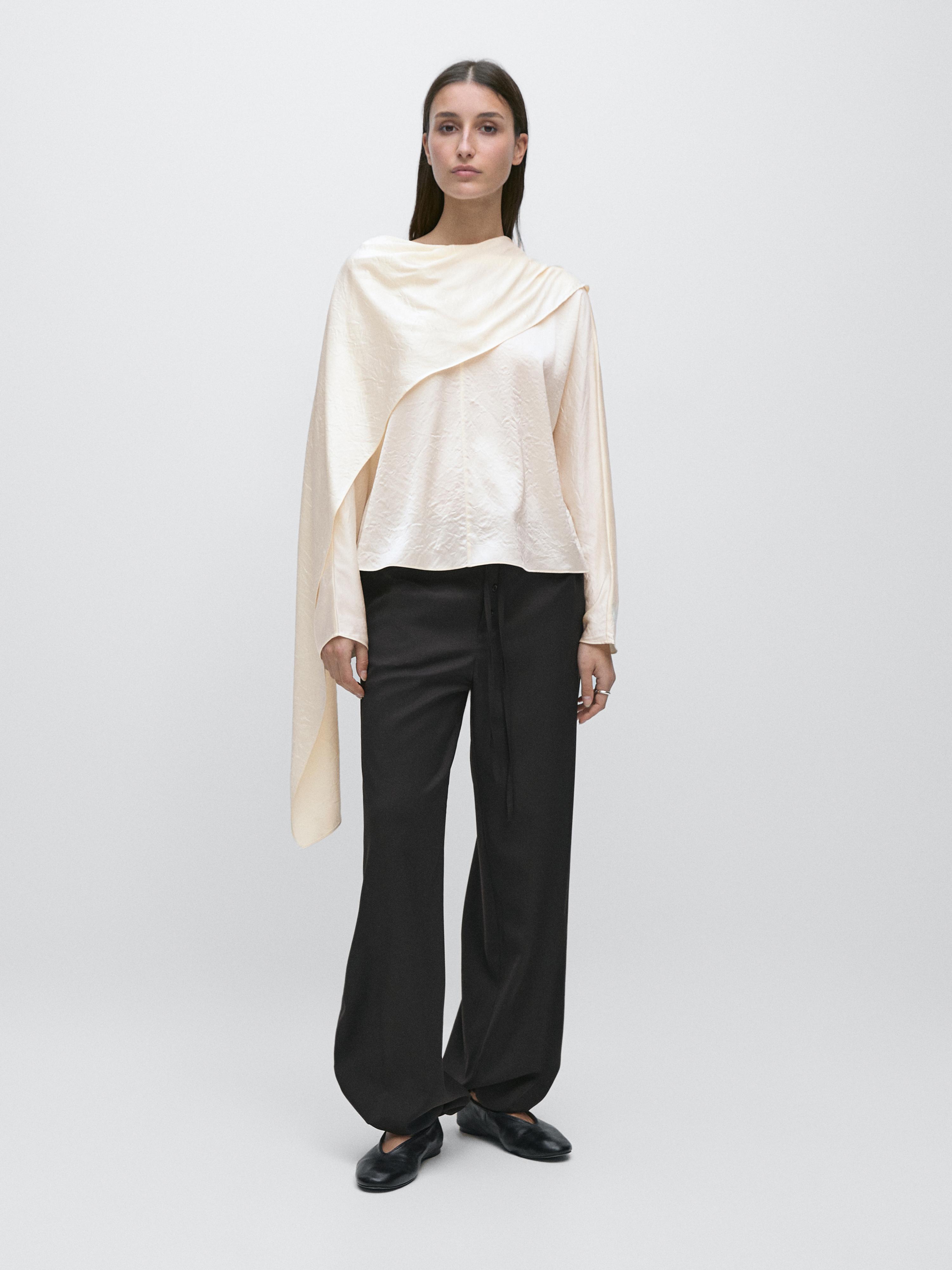 Flowy blouse set with an asymmetrical cape and black wide-leg pants.