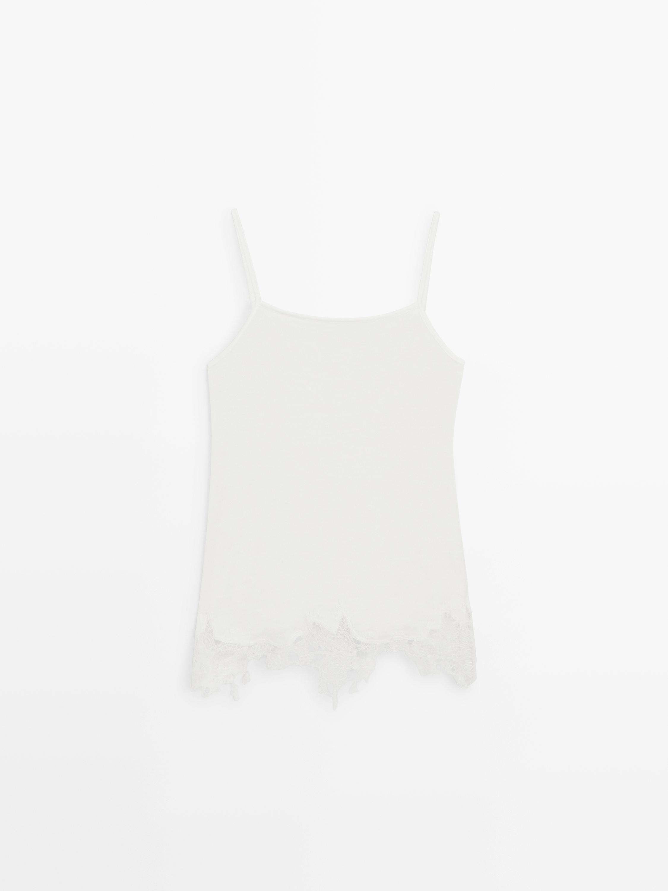 Front view of an ecru tank top with thin straps and lace detail on the hem.