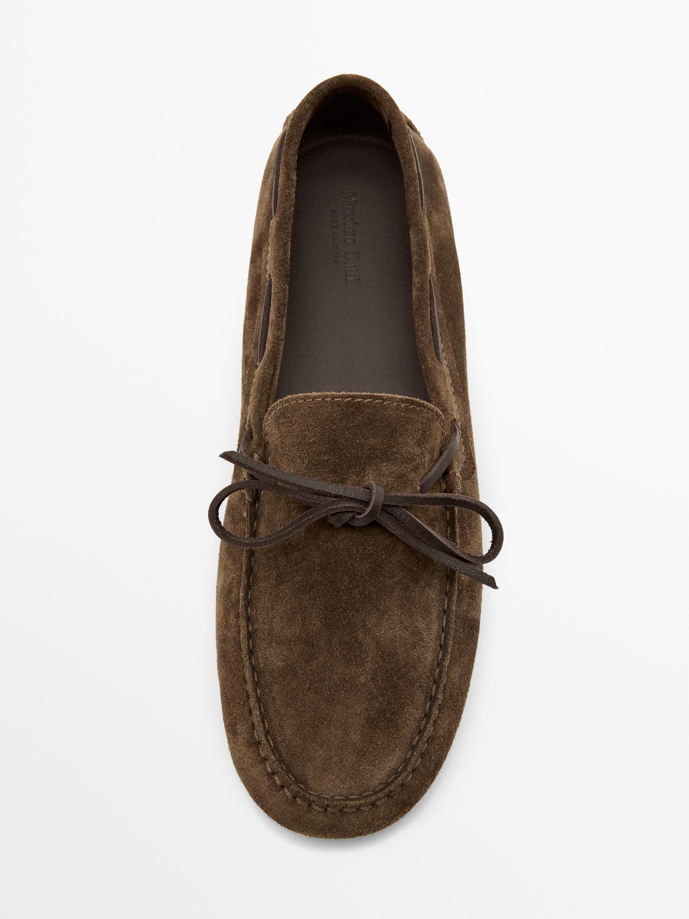 Vista superior de mocasín caqui con lazo decorativo en la parte delantera y costuras visibles.