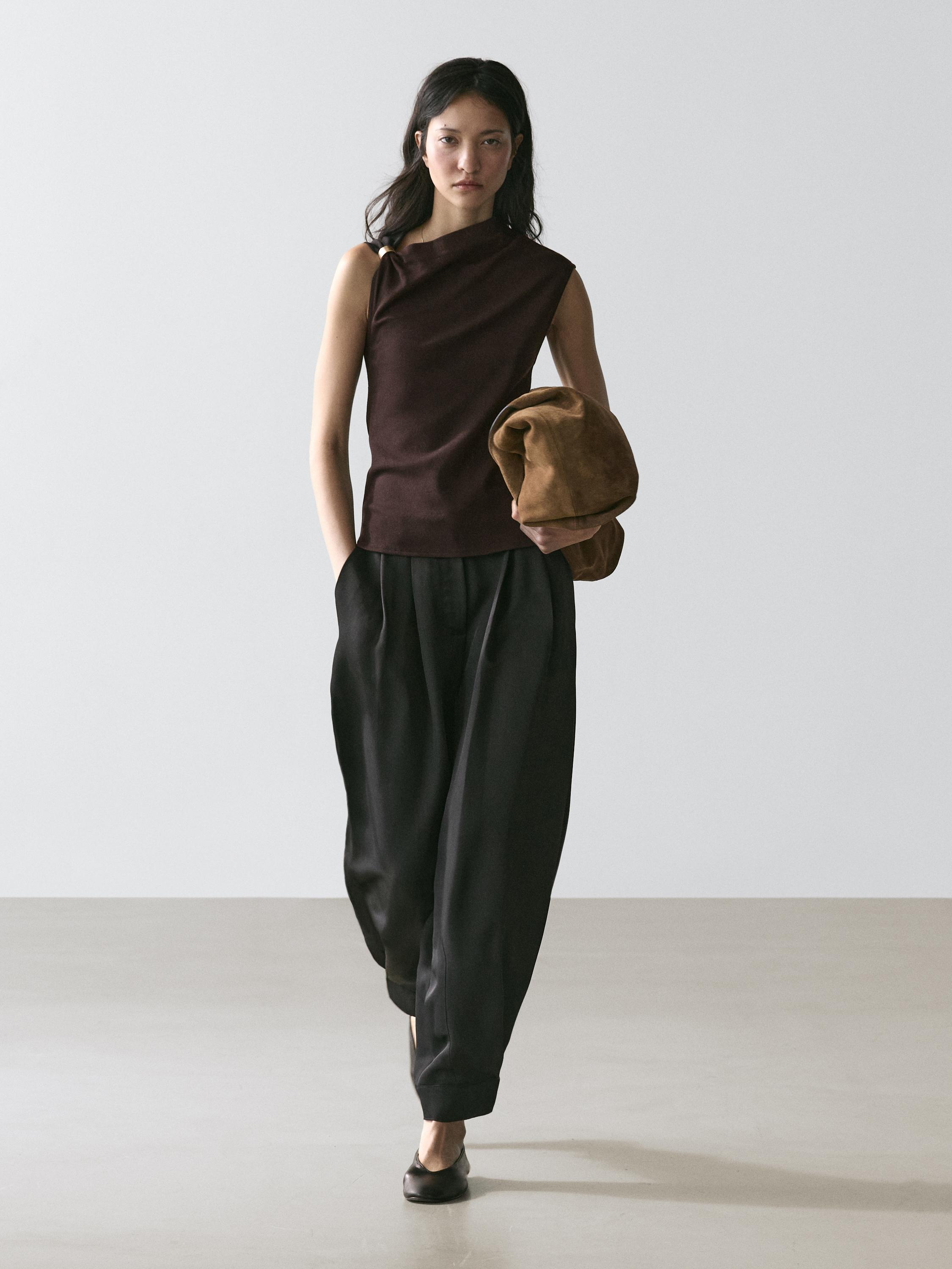 Brown sleeveless asymmetrical top and wide black pants set.