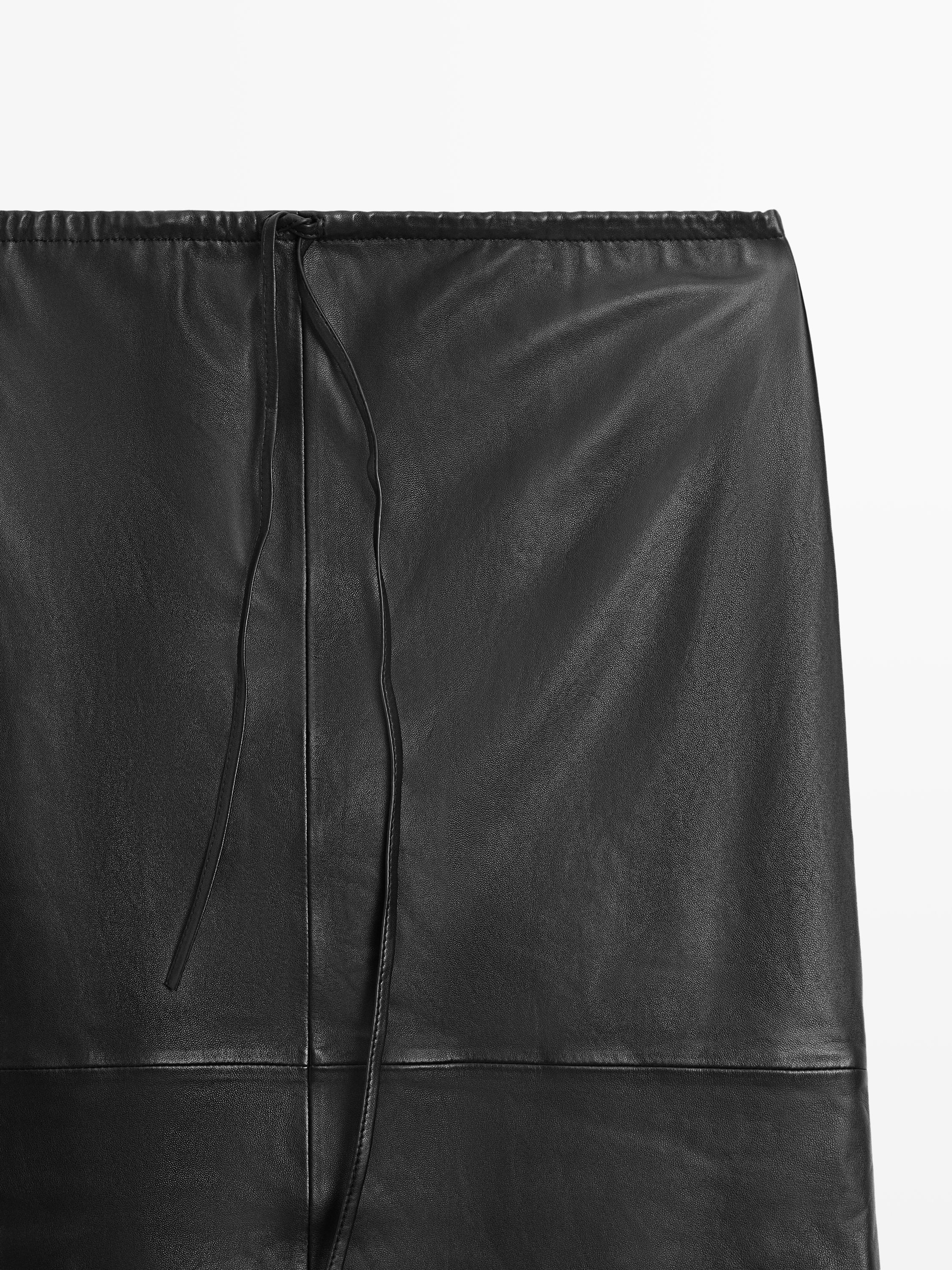 "Halbnahe Einstellung eines schwarzen Rocks mit horizontaler Naht und dekorativer Kordel am oberen Rand."