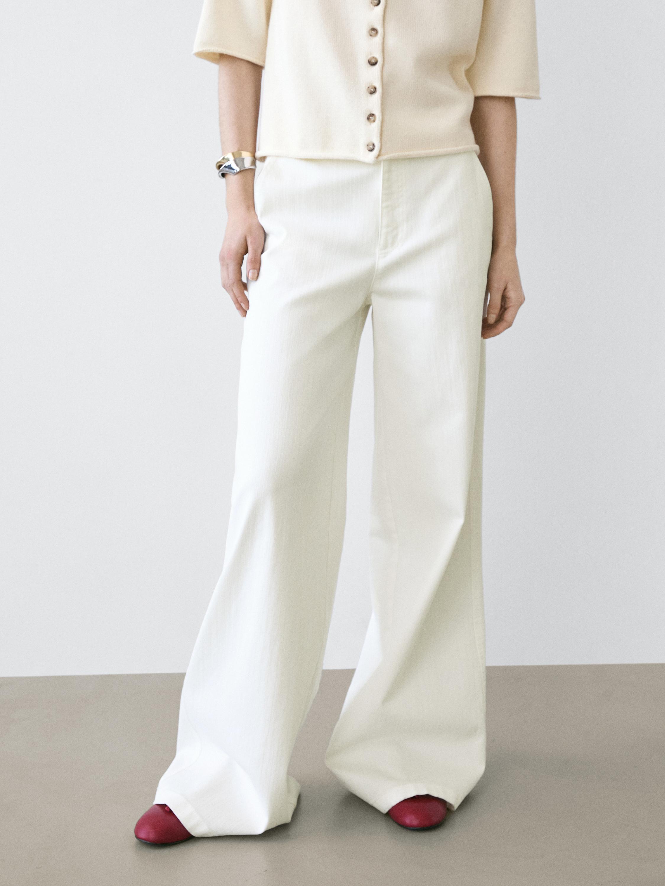Set aus weißen High-Waist-Palazzo-Hosen und beiger Bluse mit Knopfleiste.