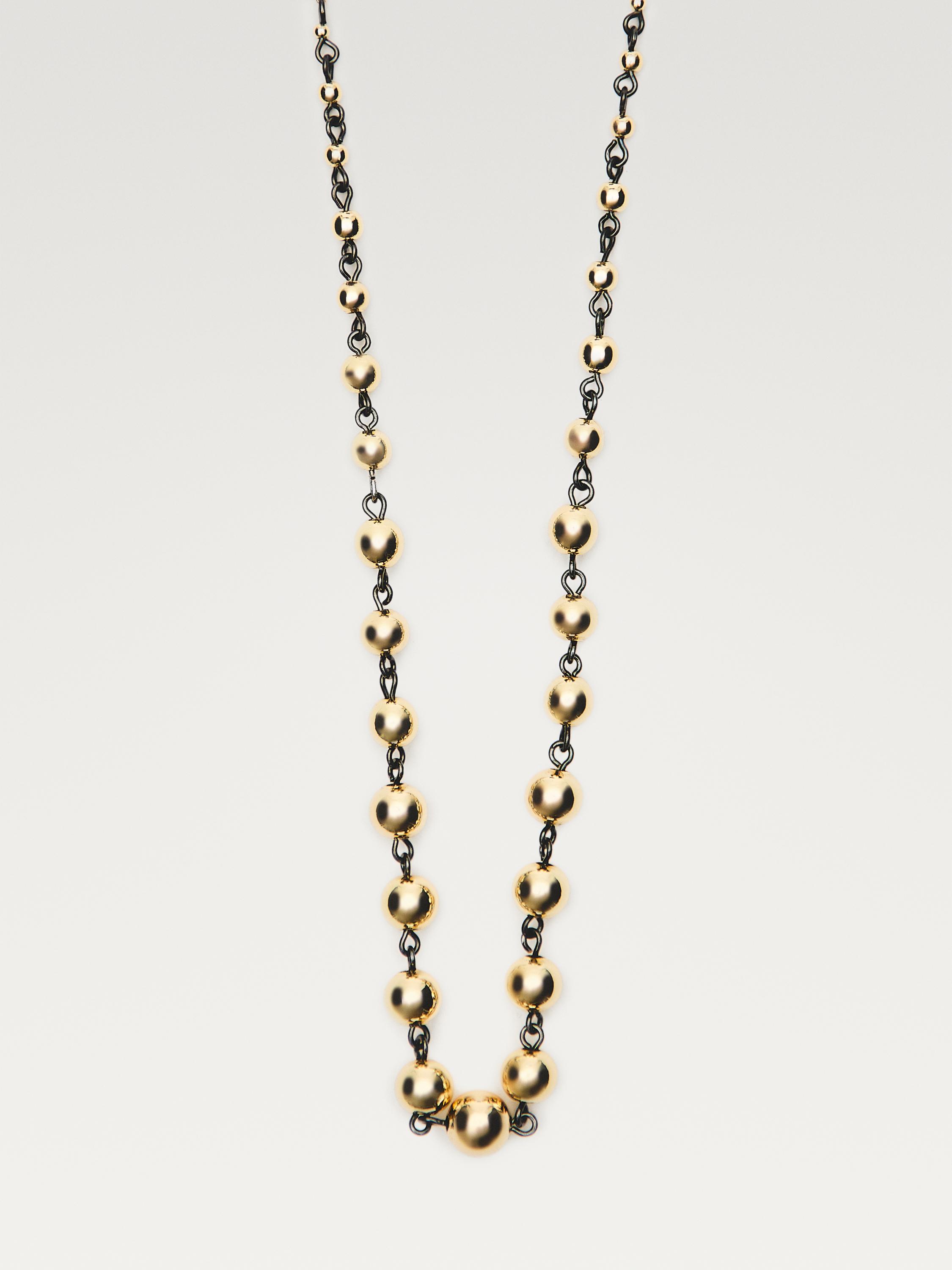 Colar de contas douradas e negras en cadea alternada.
