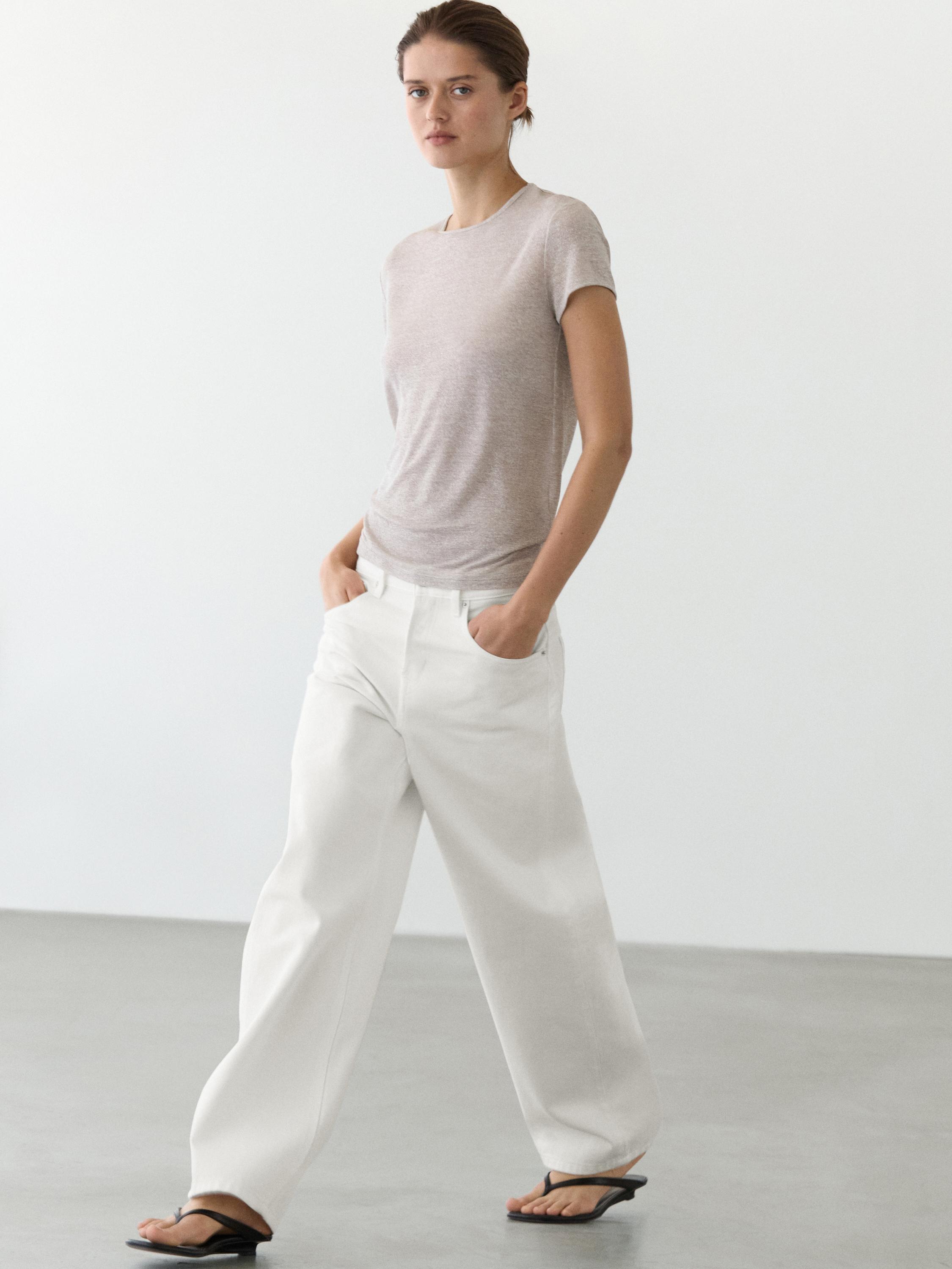 Σετ από κοντομάνικο μπλουζάκι σε παλιό πλατινέ χρώμα και φαρδιά λευκά παντελόνια με πλαϊνές τσέπες.