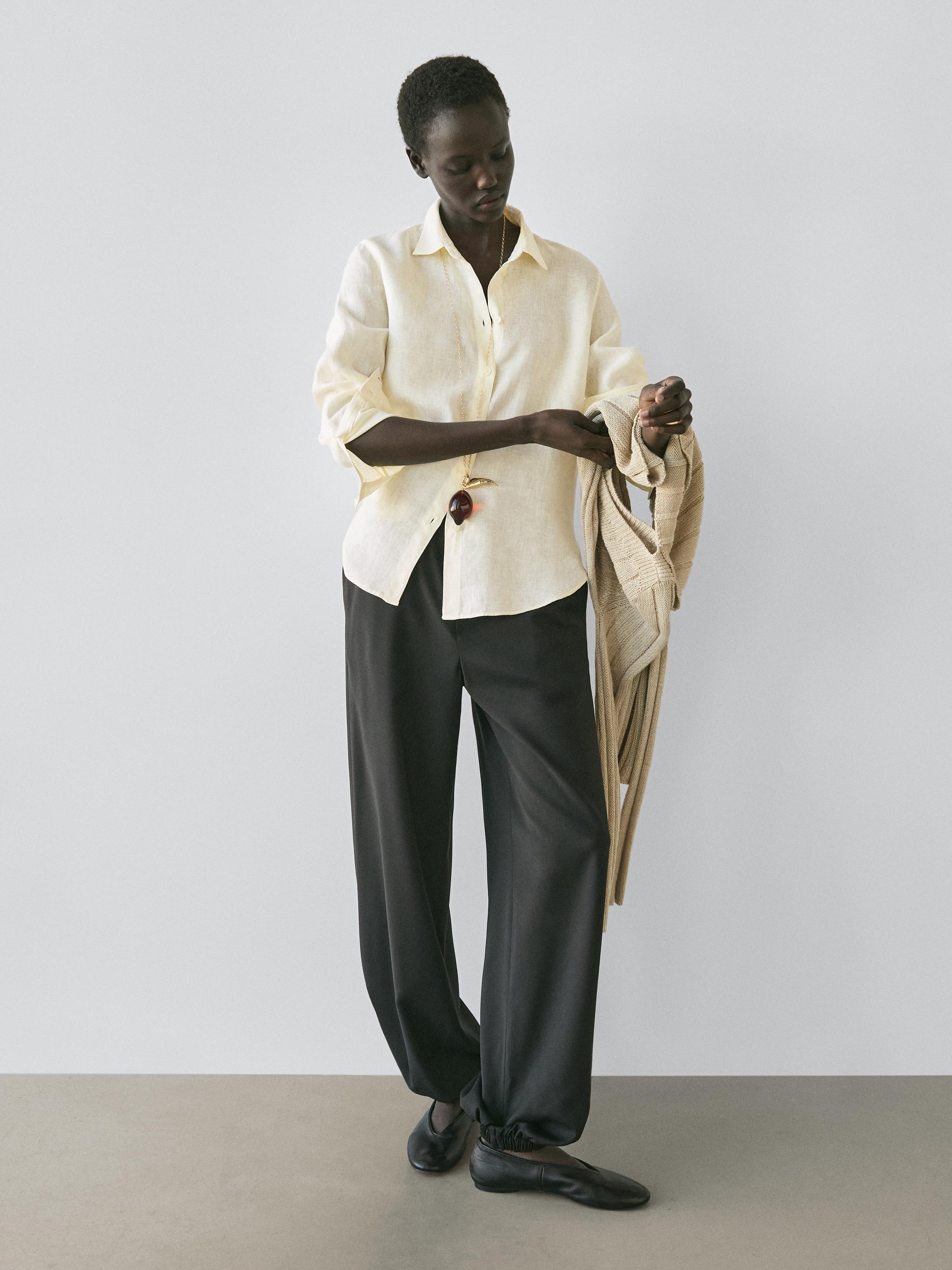 Conjunto de camisa amarilla fluida con botones y pantalones negros de pierna ancha.