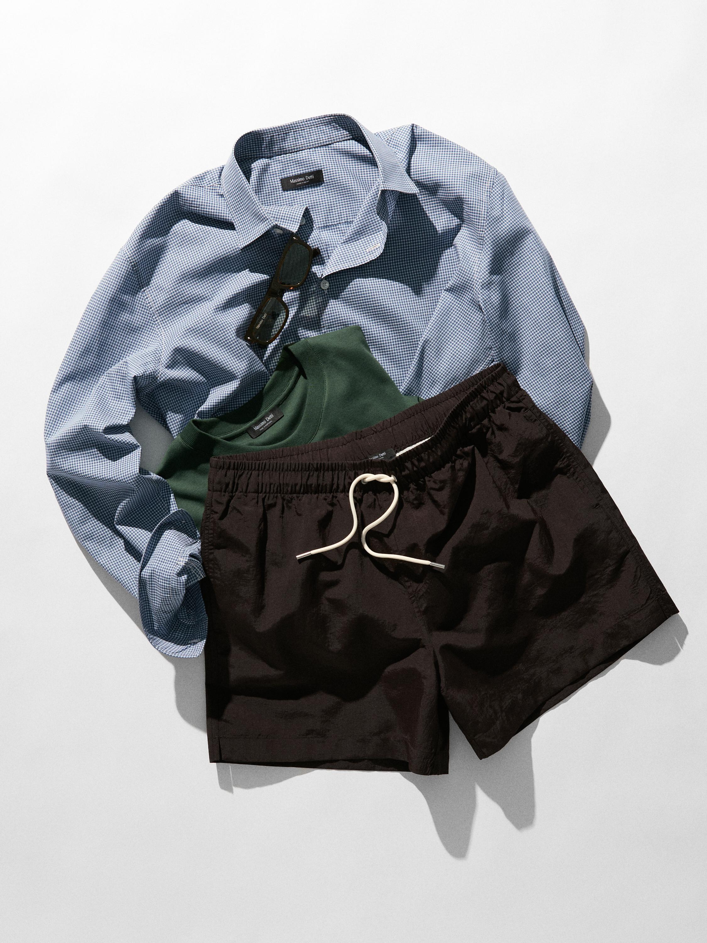 Ensemble chemise bleue à imprimé à carreaux, t-shirt vert et short noir avec cordon de serrage blanc.