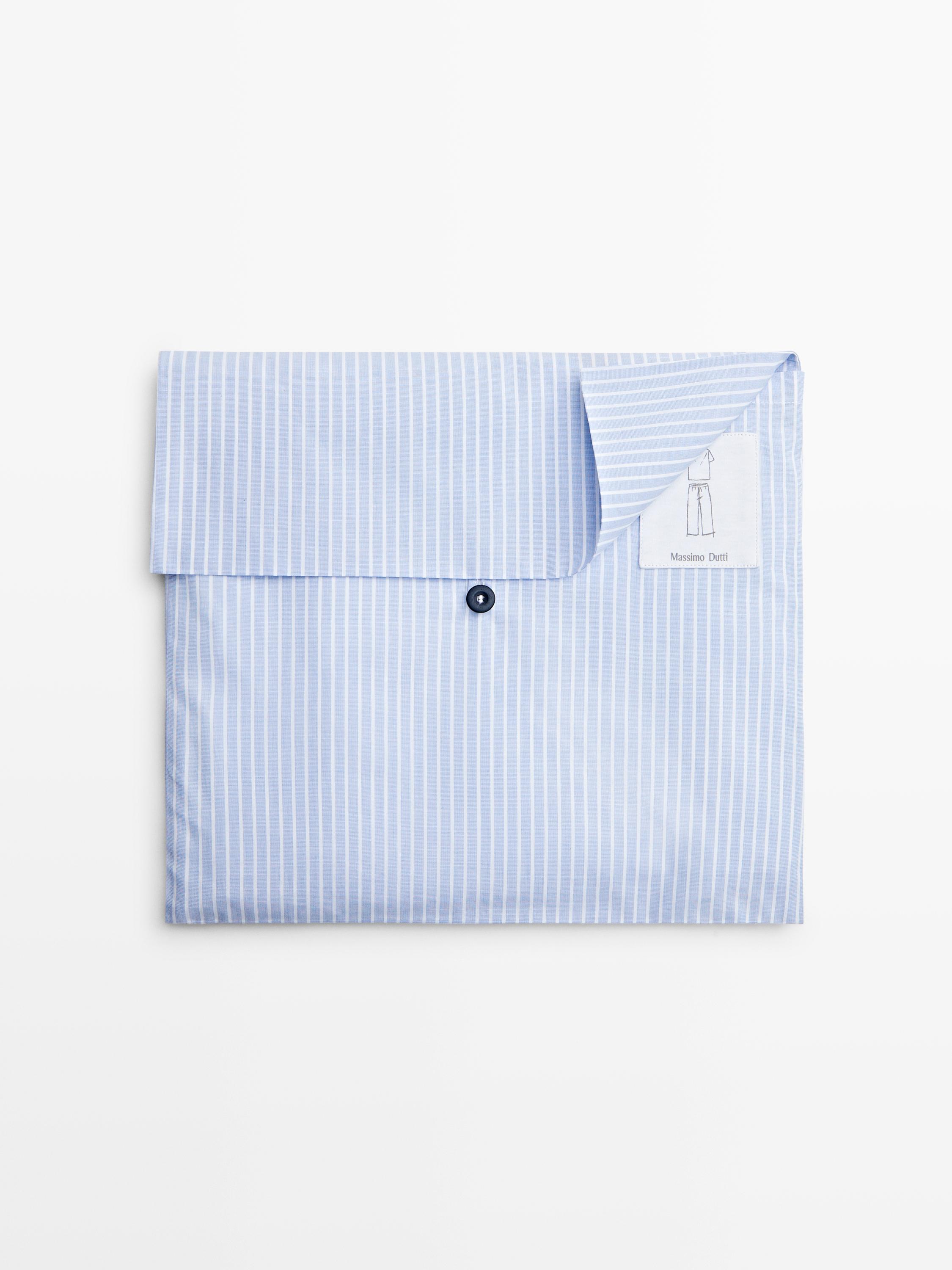 Vista frontal de pijama celeste con rayas blancas, empaquetado con botón negro visible. Etiqueta con dibujo de pijama.