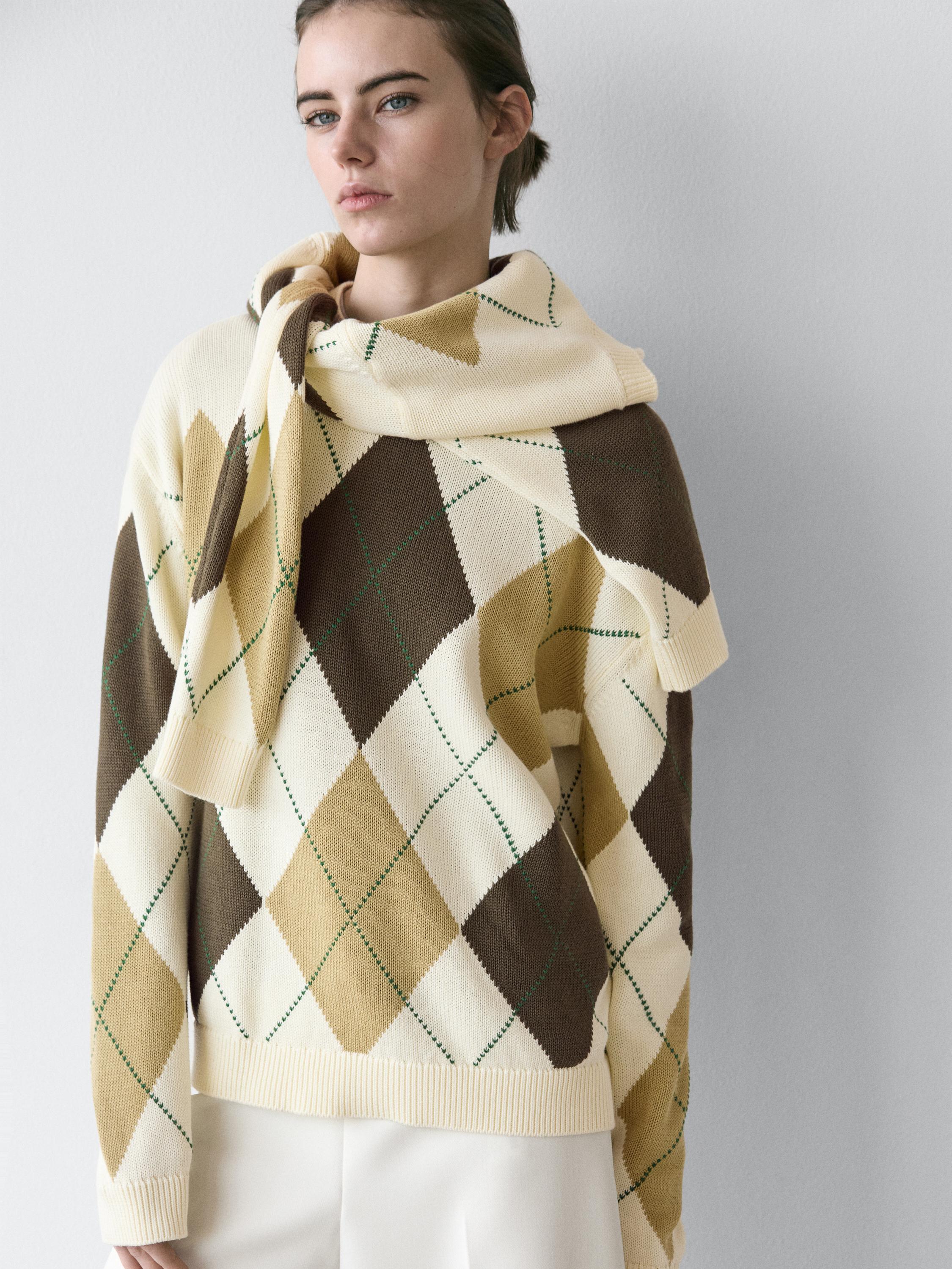 Plan moyen de pull écru avec des losanges marrons et beiges, col roulé et manches longues.