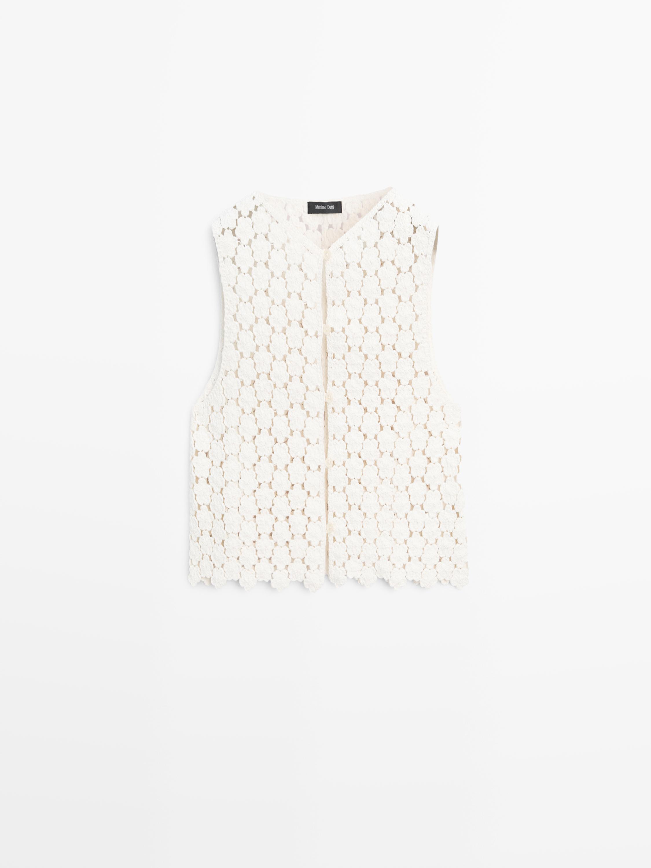 Vue de face d'un gilet écru avec un motif en crochet et des détails floraux.