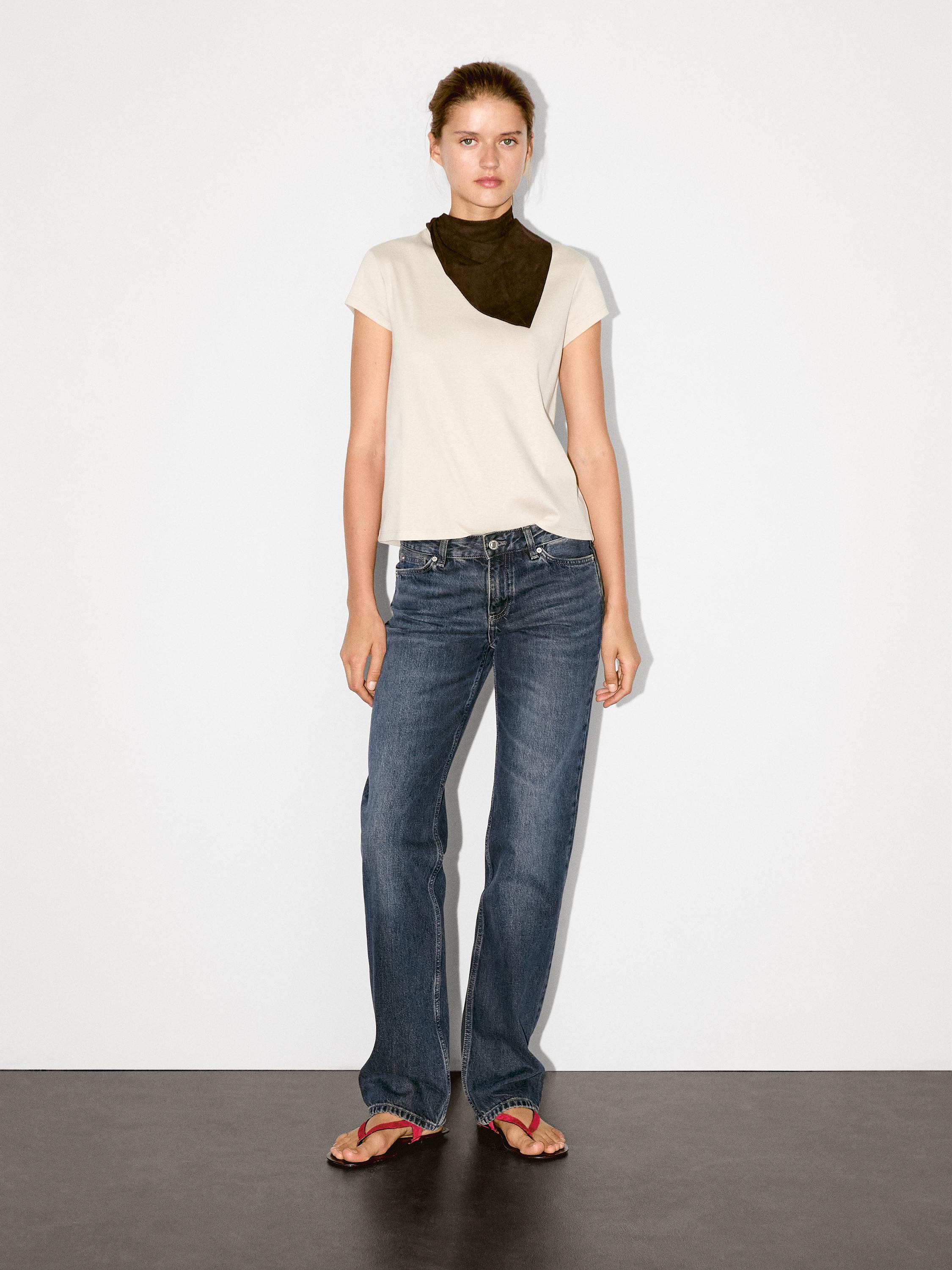 Outfit of white t-shirt, blue jeans, and red sandals. Dark scarf on the neck.