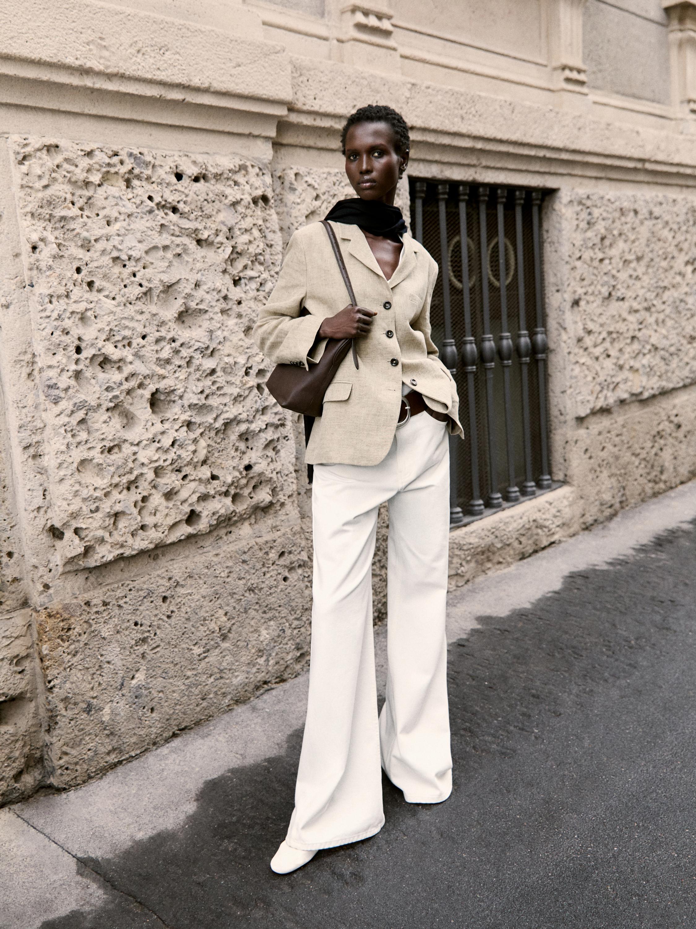 Σετ μπεζ blazer με κουμπιά, λευκό παντελόνι φαρδιάς γραμμής και μαύρο φουλάρι.