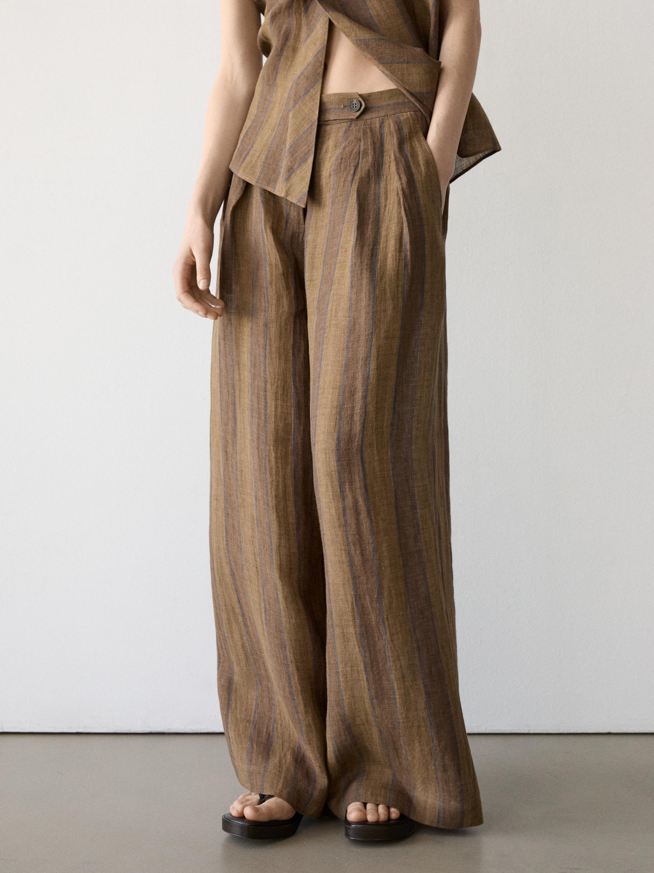 Kaki koloreko marradun praka zabalen multzoa, alboetan poltsikoak eta botoi-itxiera dituena, bat datorren toparekin konbinatuta.