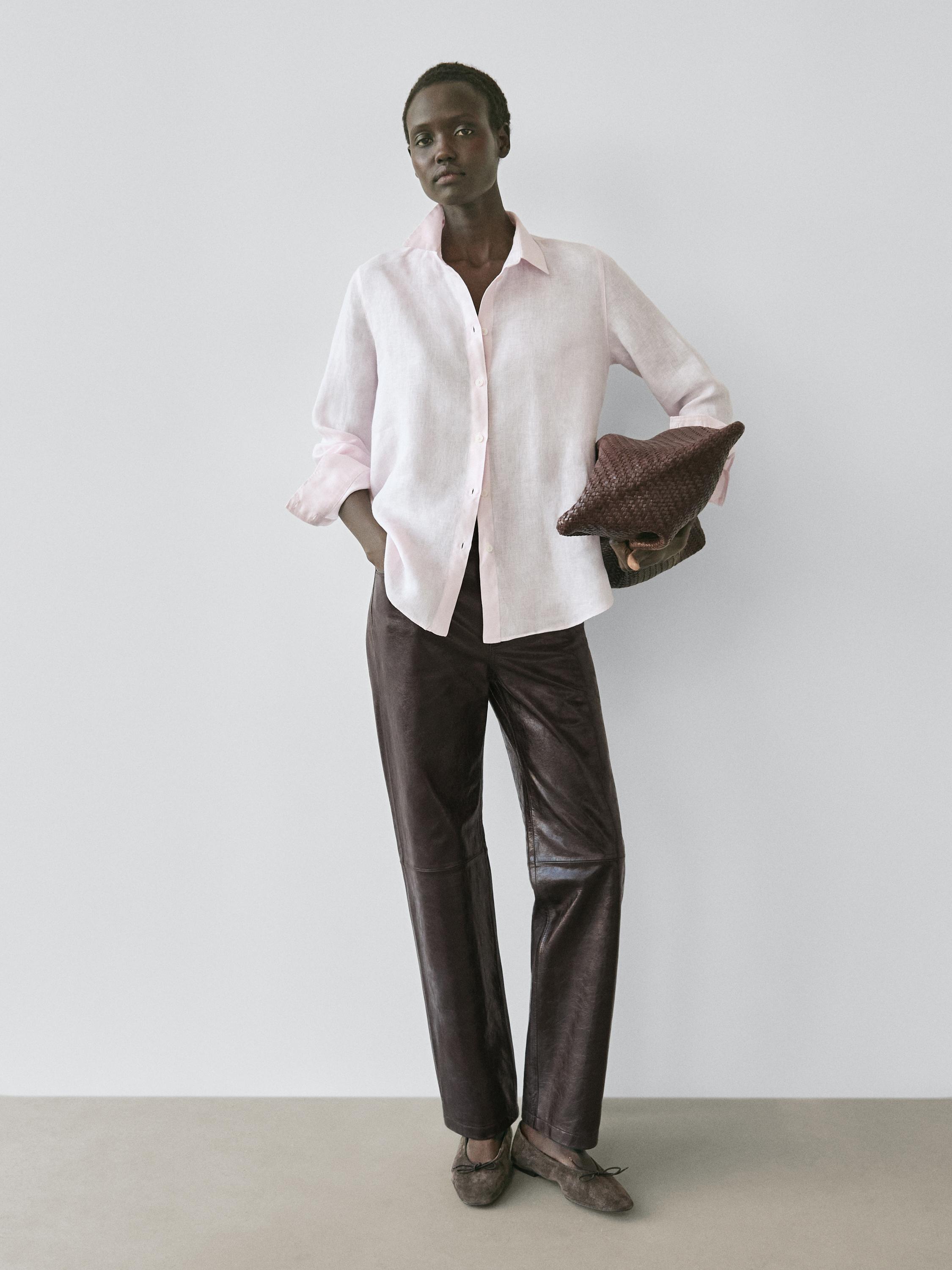 Conjunto de camisa rosa fluida con botones y pantalones marrones.