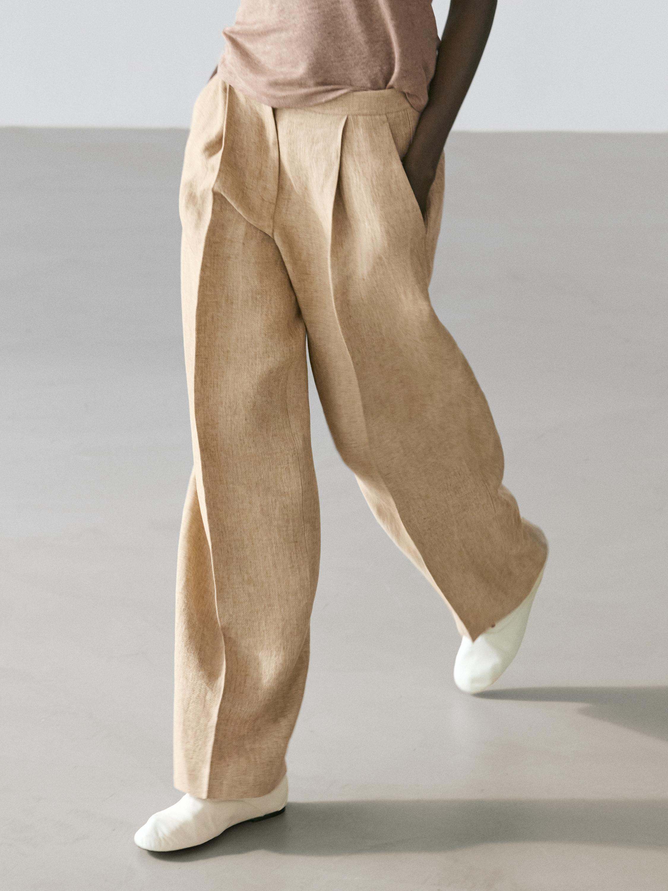 Set van een vloeiende beige broek met plooien en zijzakken.