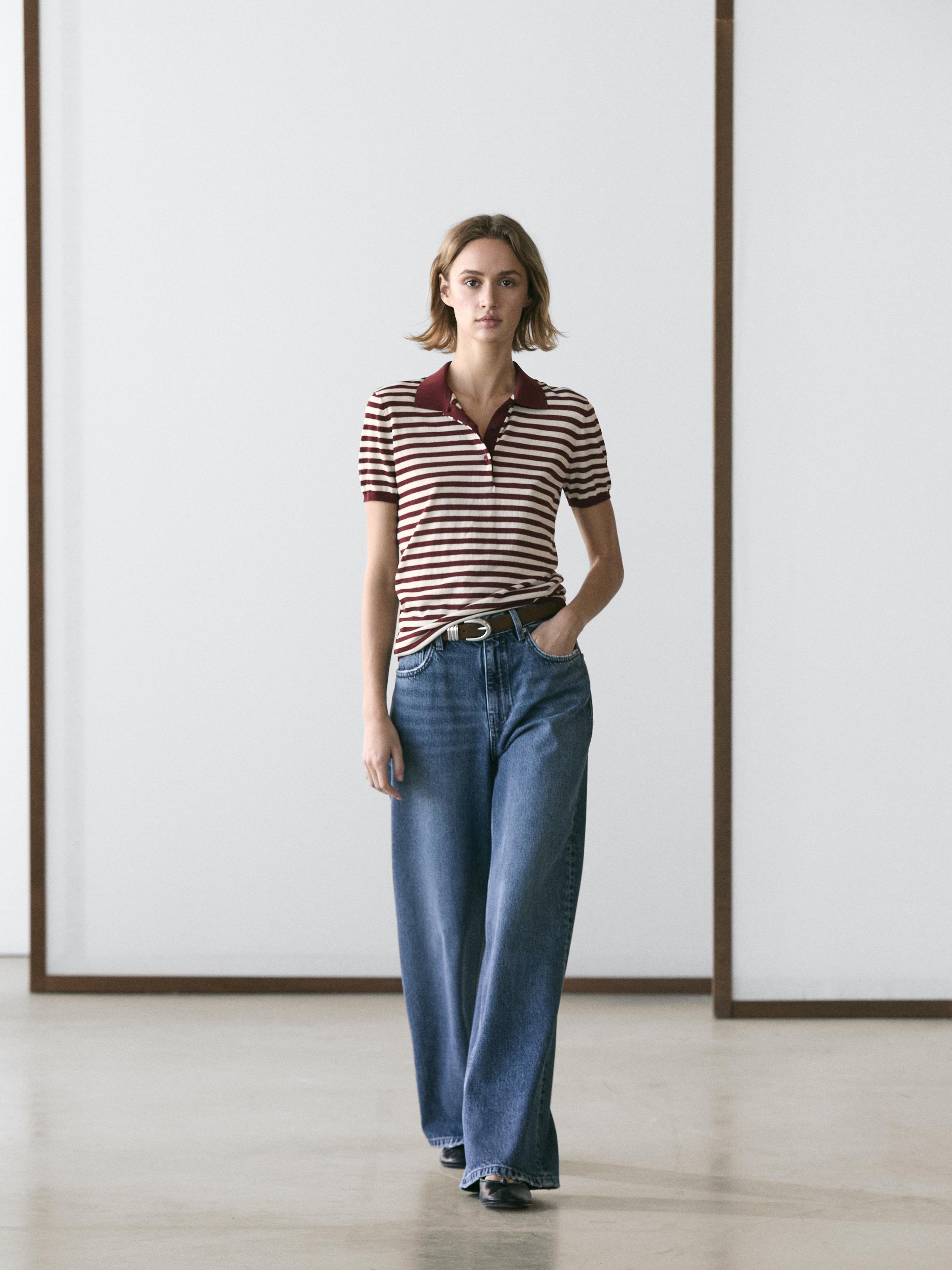 Conjunto de polo burdeos a rayas con cuello y jeans anchos azules con bolsillos laterales.