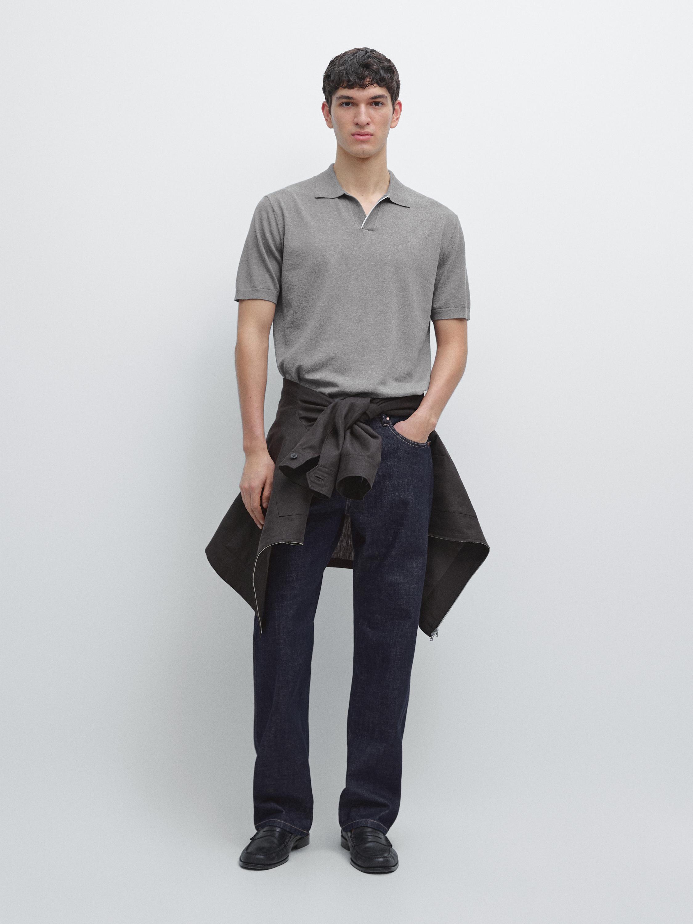 Short-sleeved gray polo shirt, dark pants, and a jacket tied around the waist.