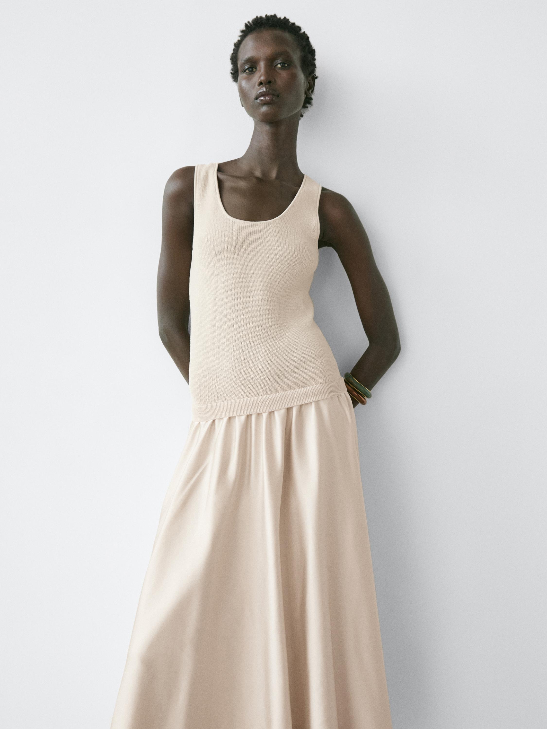 Conjunto de vestido beige de tirantes con falda larga y vuelo.