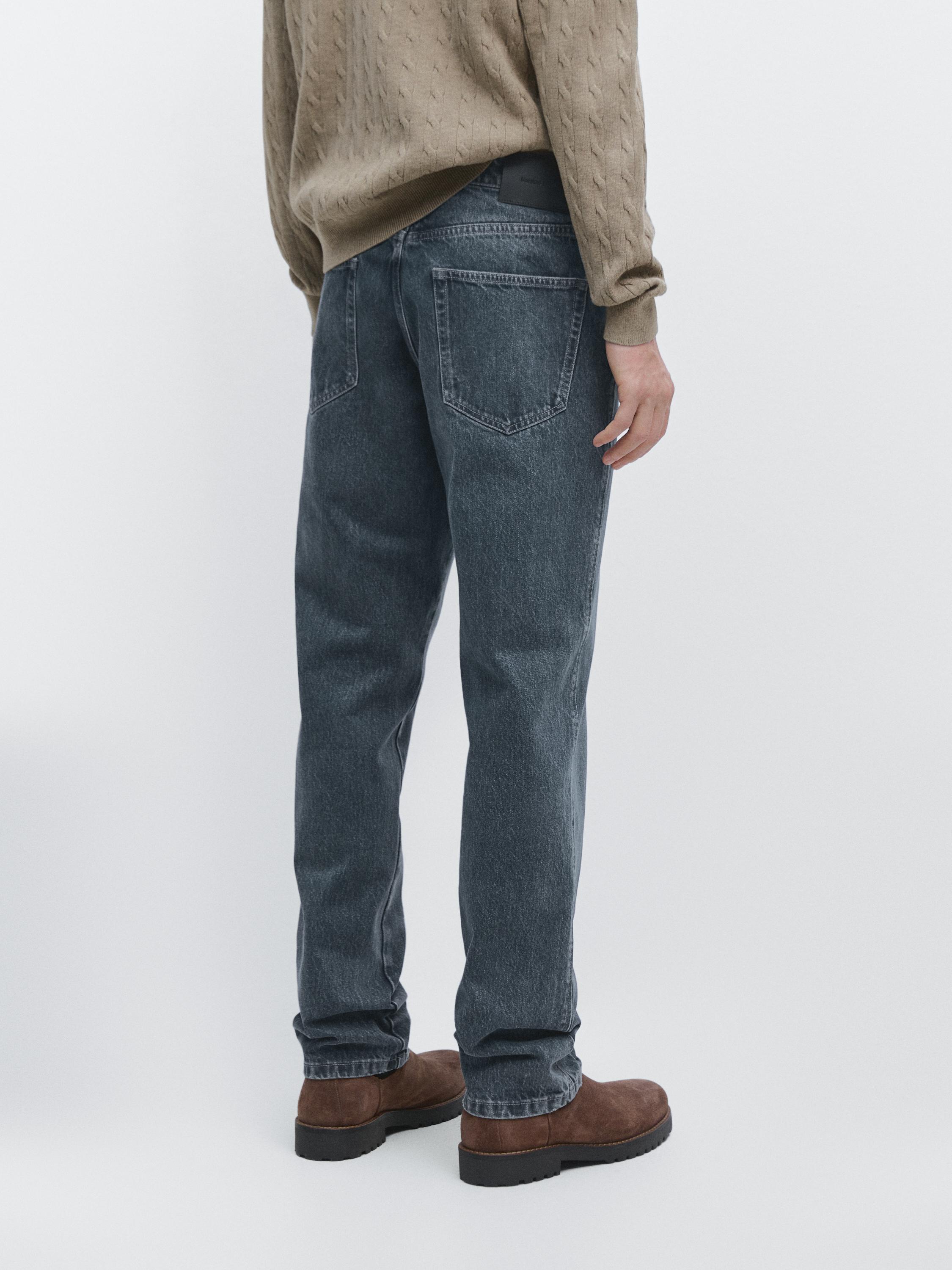 Conxunto de jeans azul tapered fit con petos traseiros visibles.