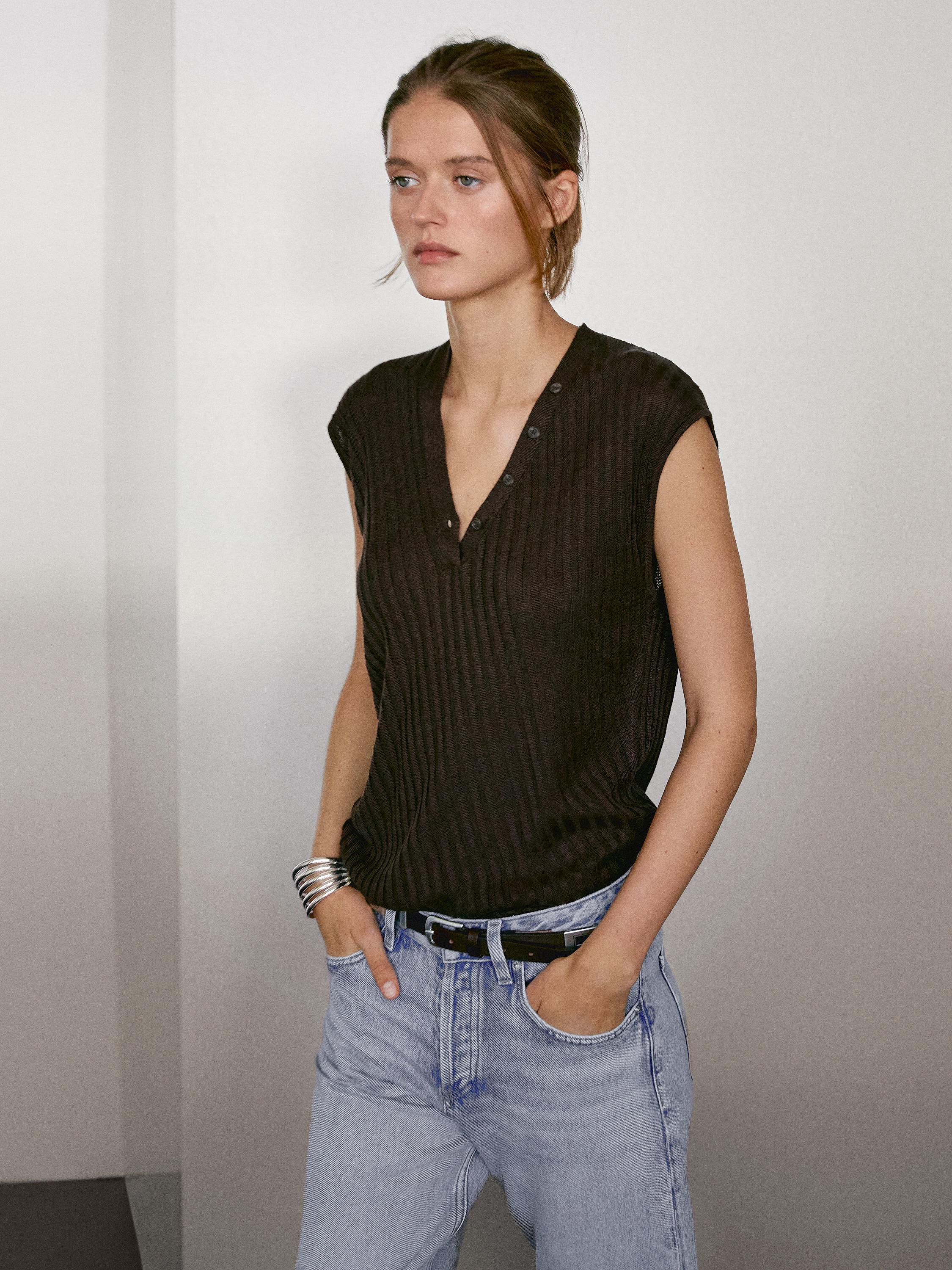 طقم يتكون من تي شيرت أسود بأزرار وبنطلون جينز فاتح.