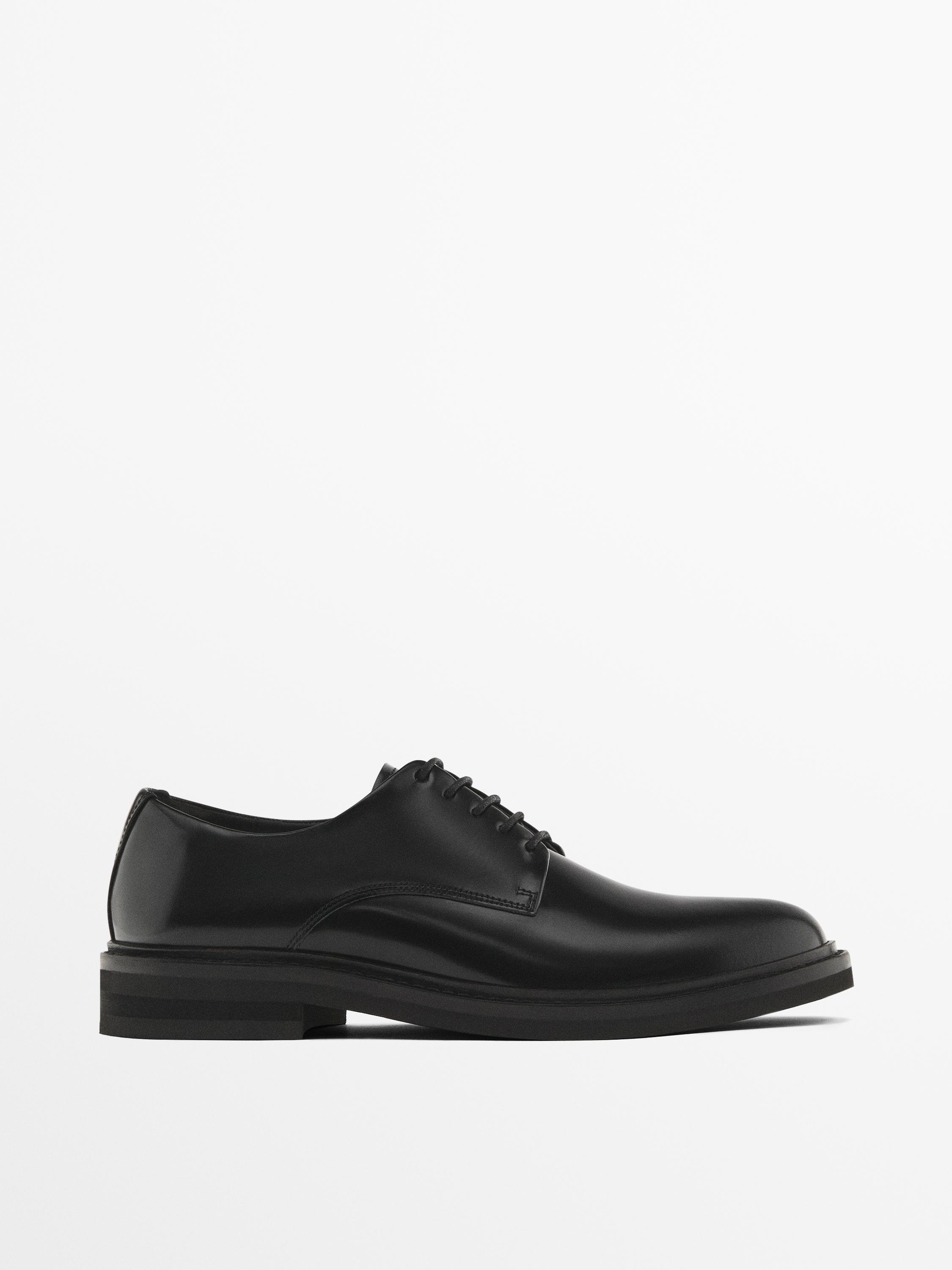 Side view of a black lace-up dress shoe with a thick sole.