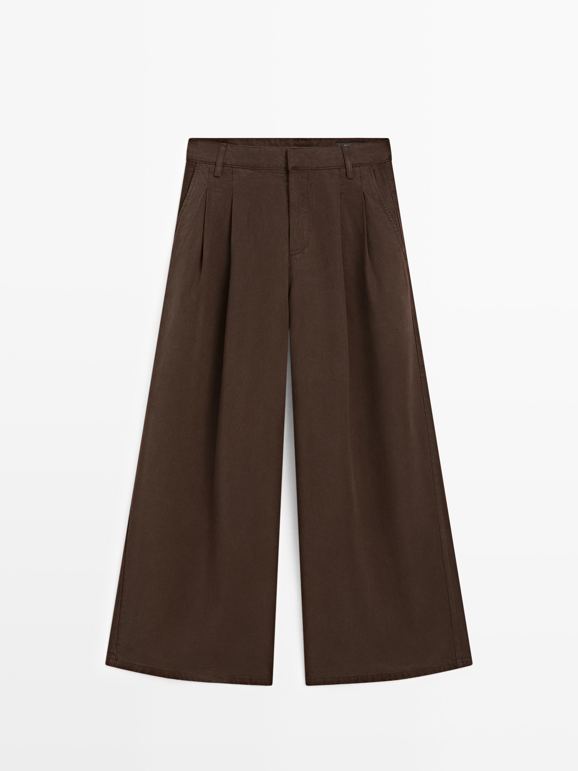 Vista frontal de pantalón chocolate wide leg con pliegues y bolsillos laterales.