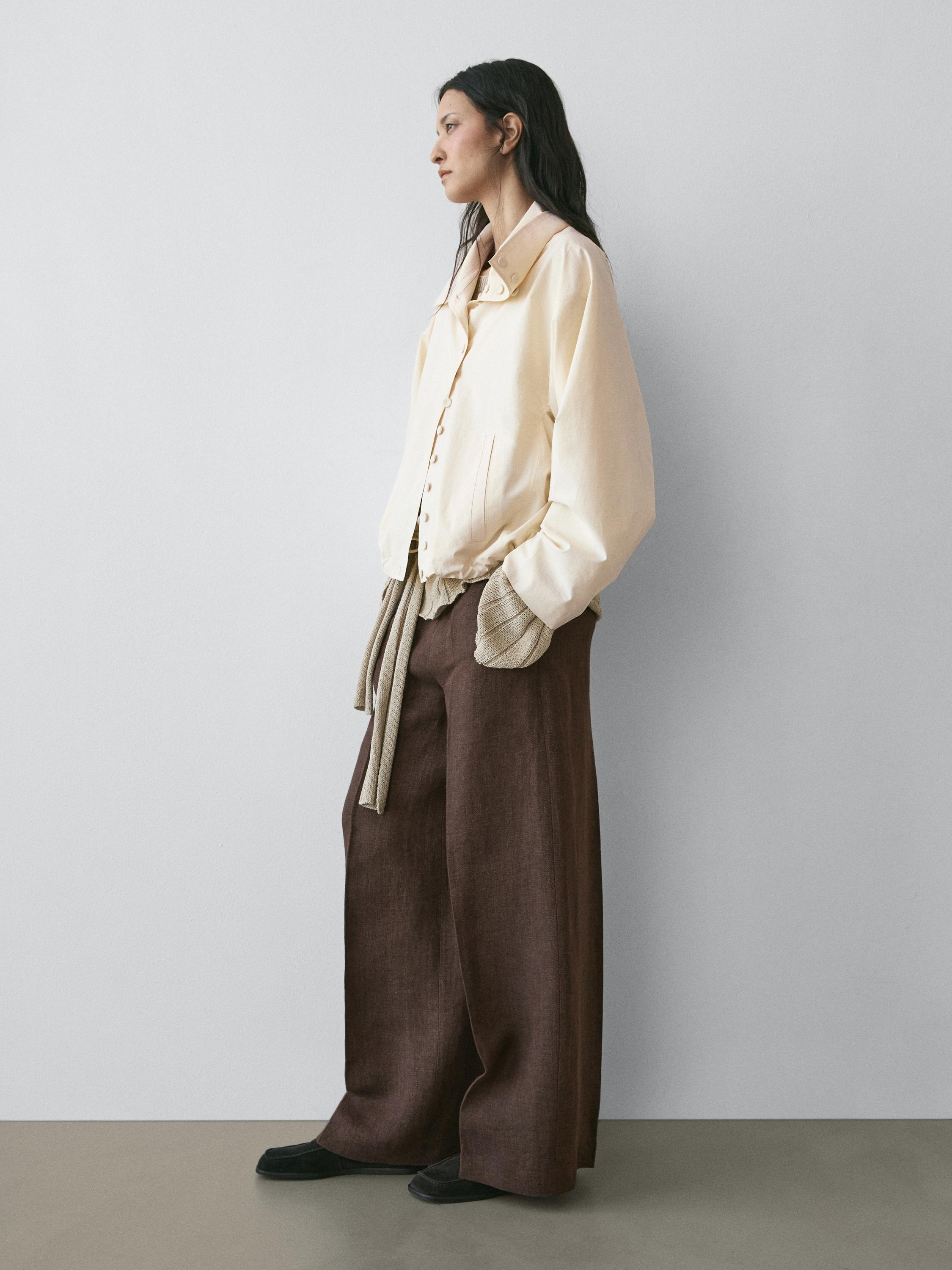 Tugmachali bej rangli bluzka va keng jigarrang shimlar toʻplami. Bluzkada yon choʻntaklar koʻrinib turadi.