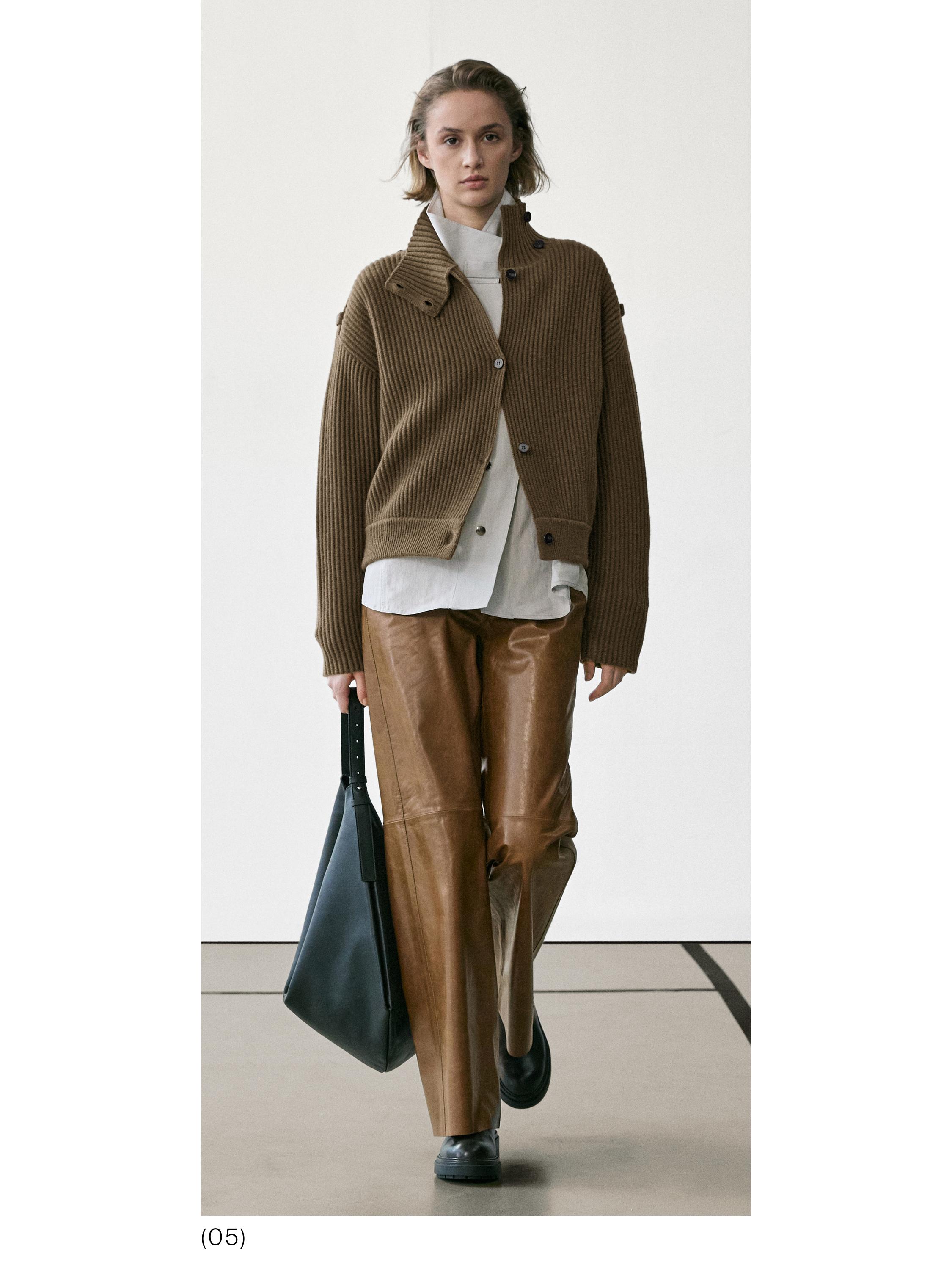 Conjunto de chamarra café de punto con botones, camisa blanca, pantalones cafés y bolsa negra.